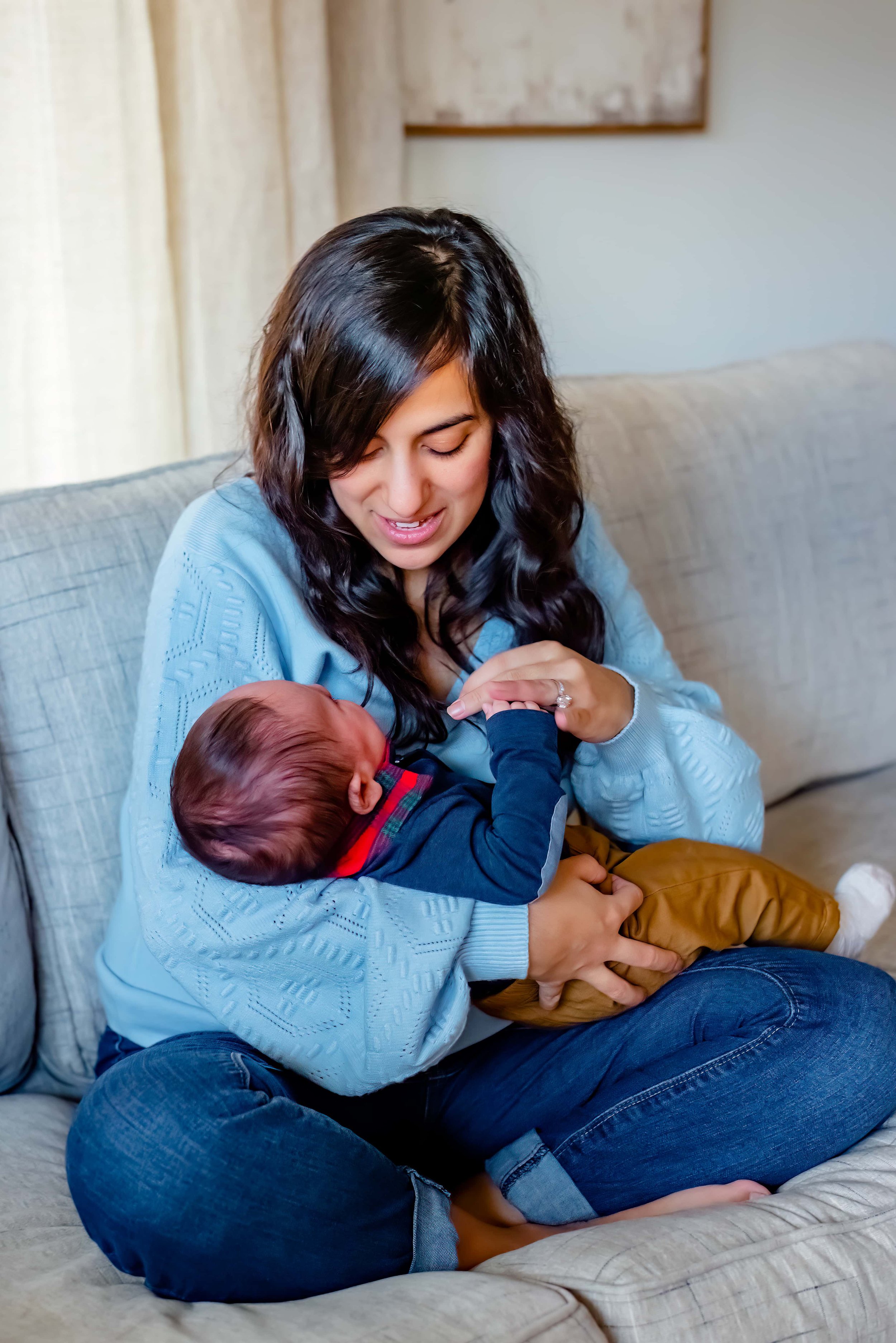 Newborn photograph with mom cradling baby and playing with his hand