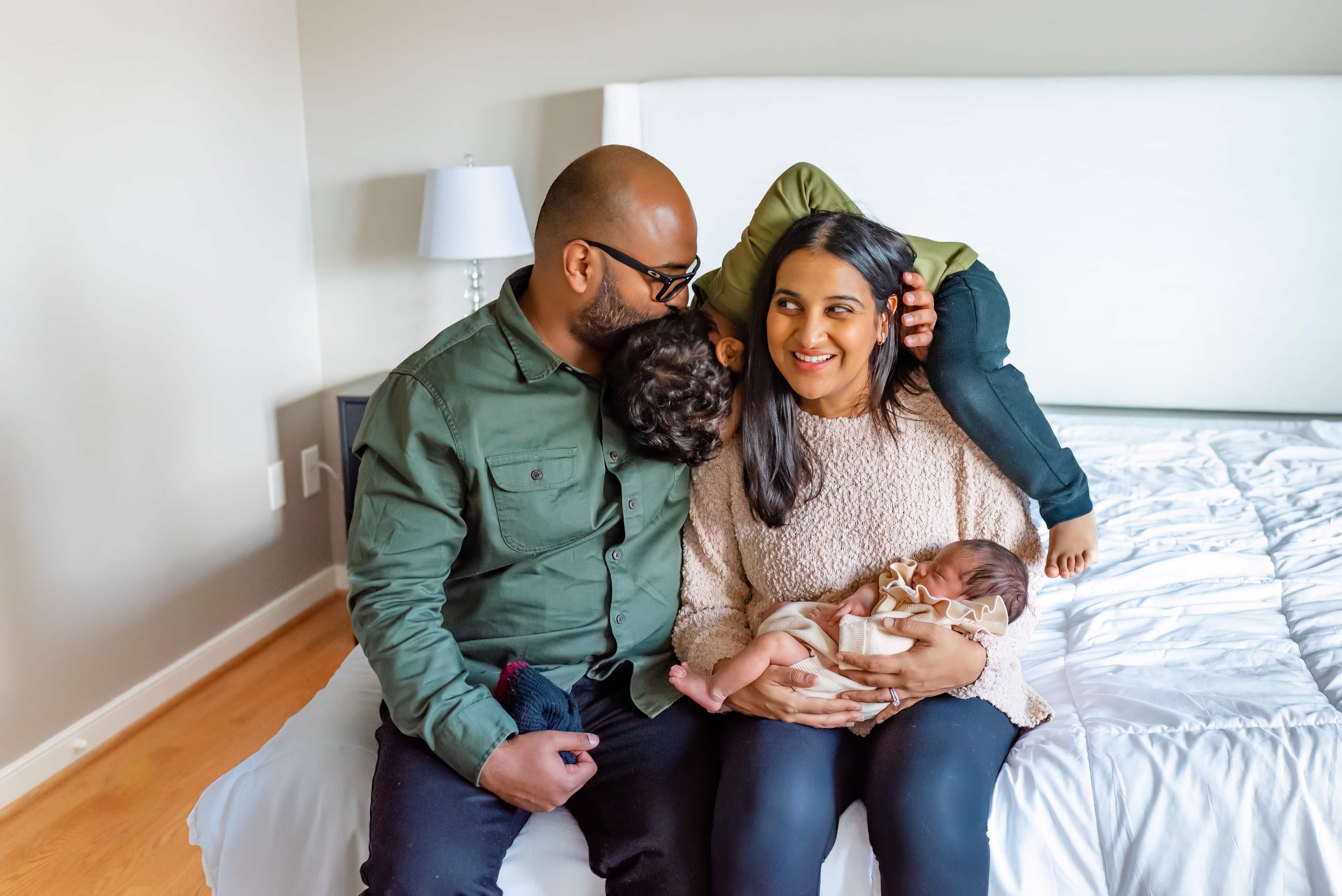 Maryland Newborn Photographer - Mom, dad, toddler and baby playing on the bed