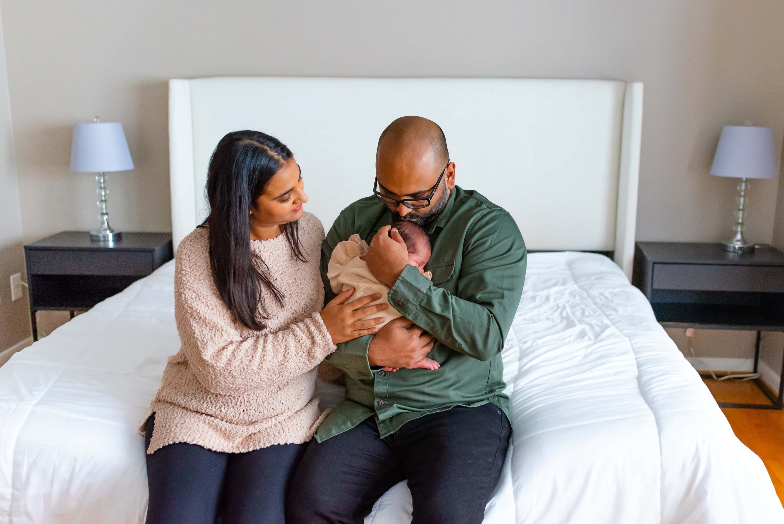 Newborn photograph of mom, baby and dad cuddling on a bed