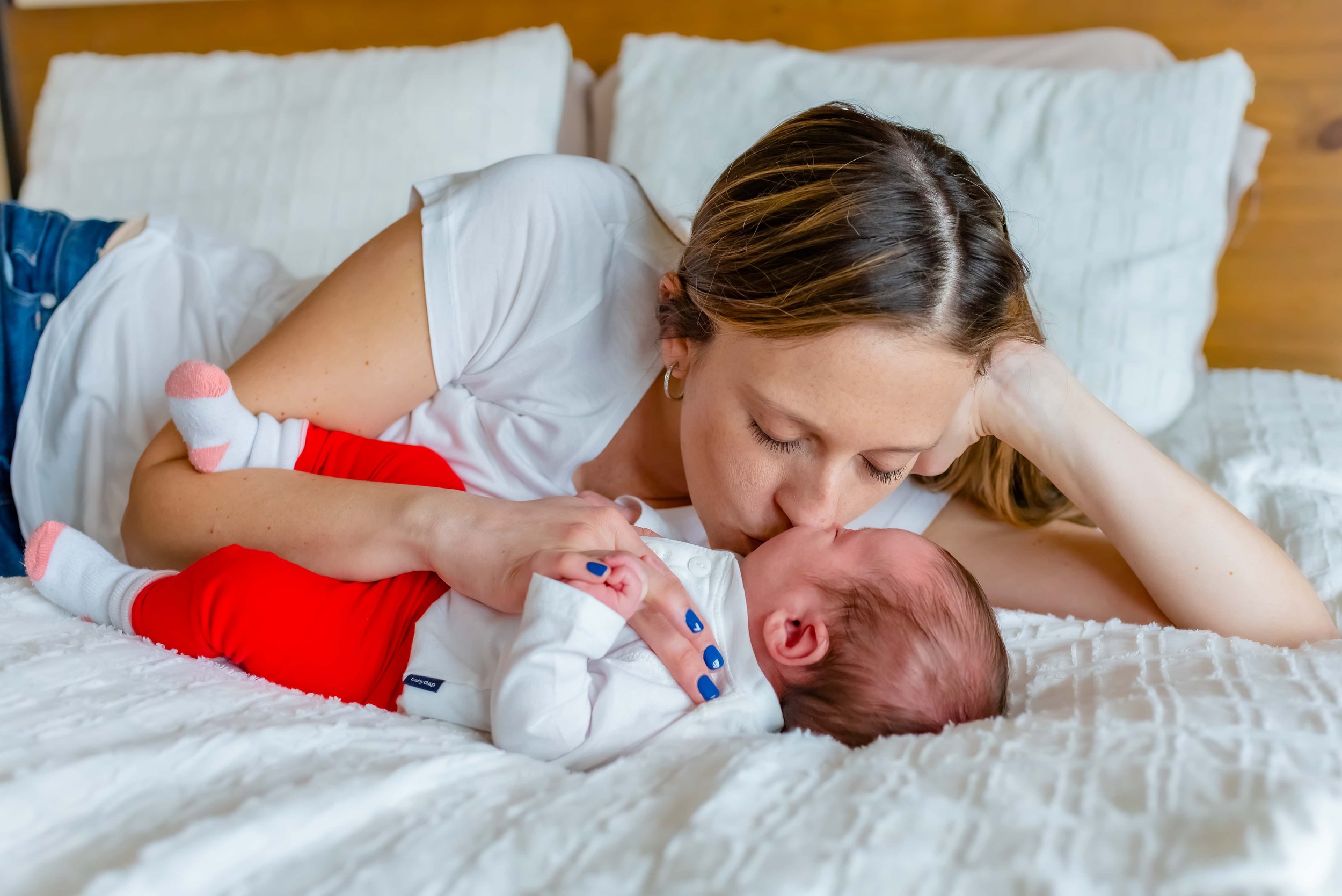 Lifestyle Newborn Photographer photo of mom kissing baby 