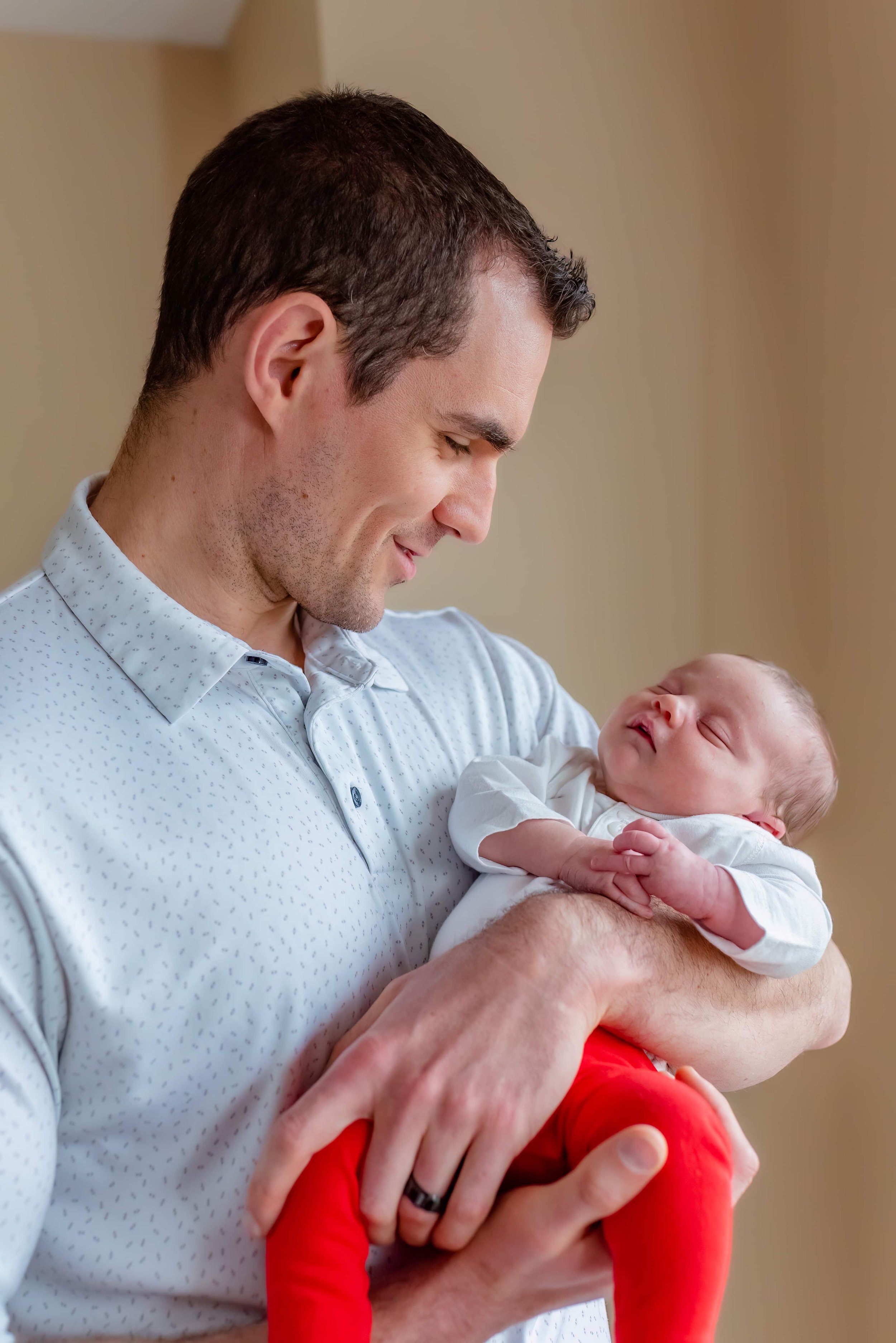 Maryland Lifestyle Newborn Photographer - Dad Cradling Baby and Smiling