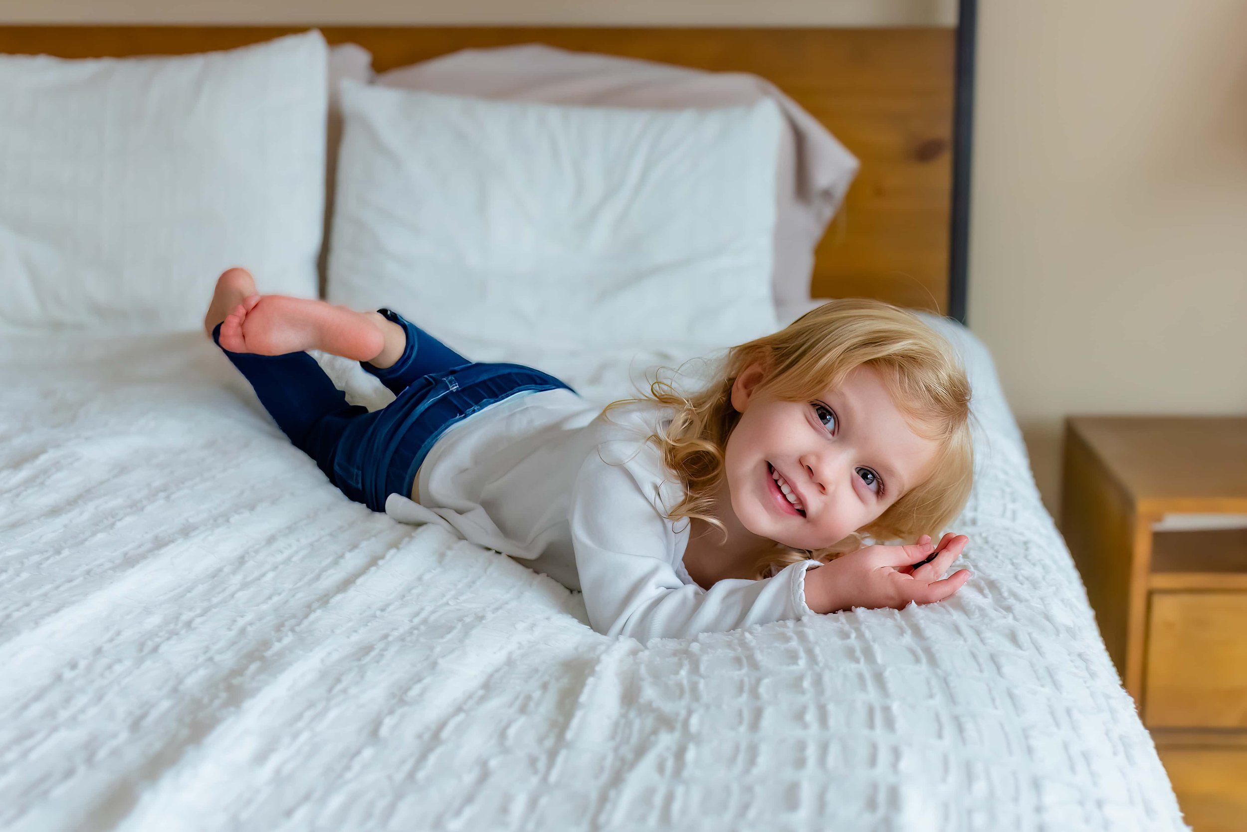 Maryland Lifestyle Newborn Photographer - little girl playing on a bed at a newborn session 