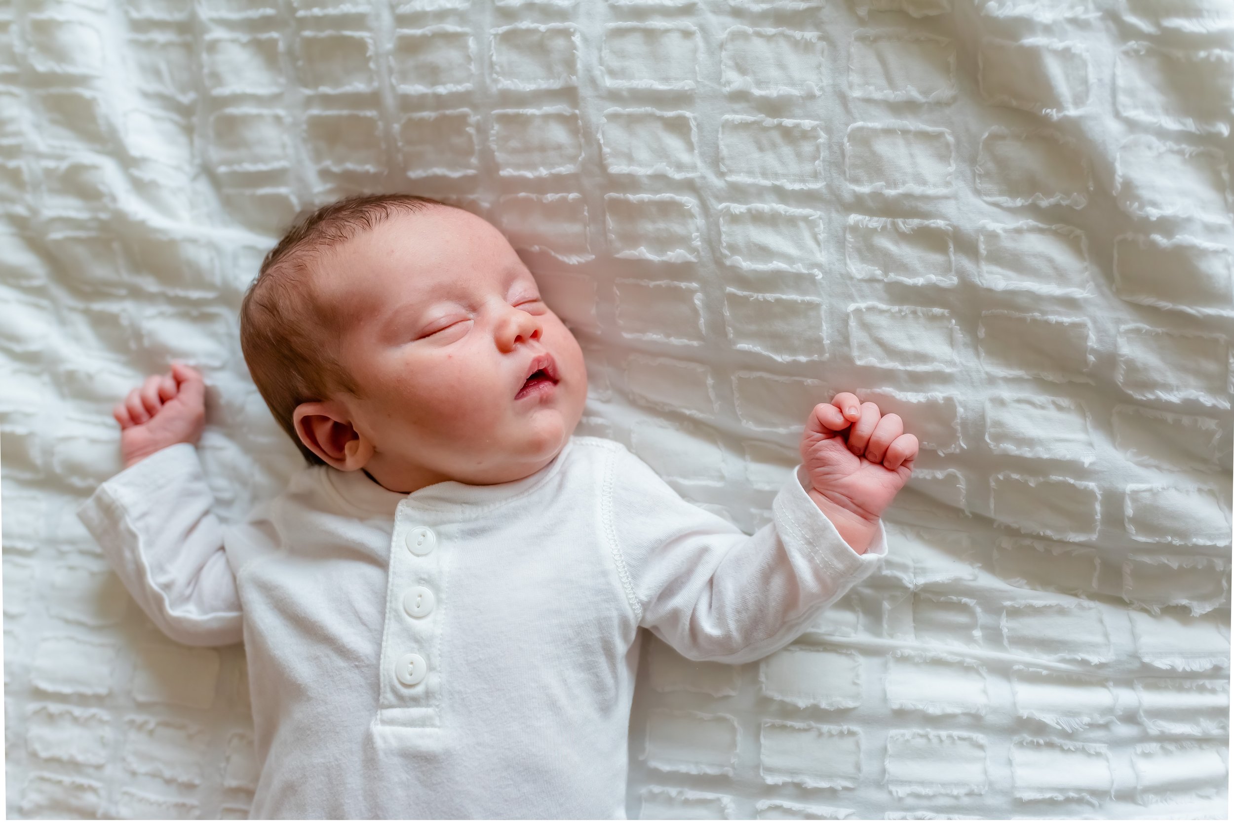 Lifestyle newborn photographer - newborn baby asleep on the bed