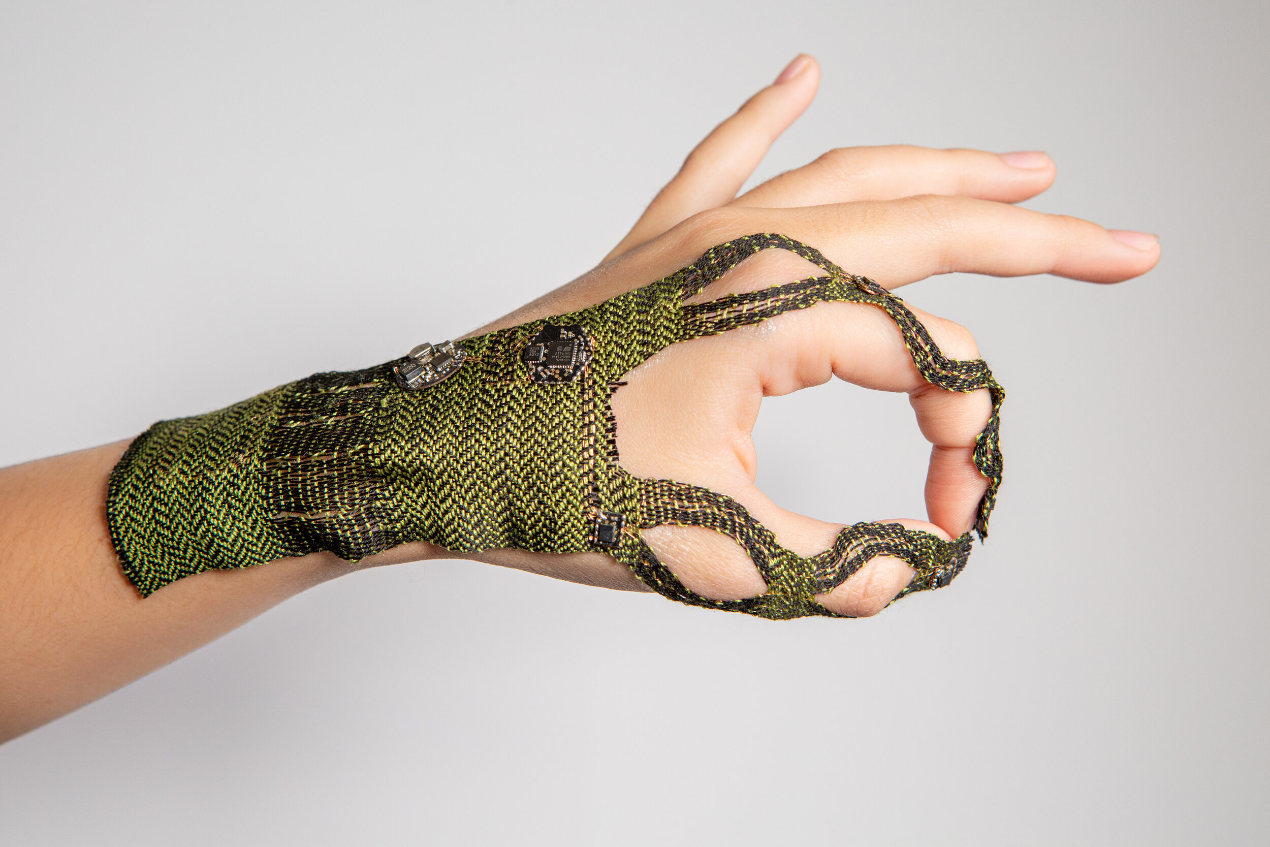  WovenProbe, the index-finger and thumb-based inertial measurement unit (IMU) tracking system explored in this project. It includes a woven bandage-like interface that supports complex on-skin circuitry: four IMUs on the tips and ends of the thumb an