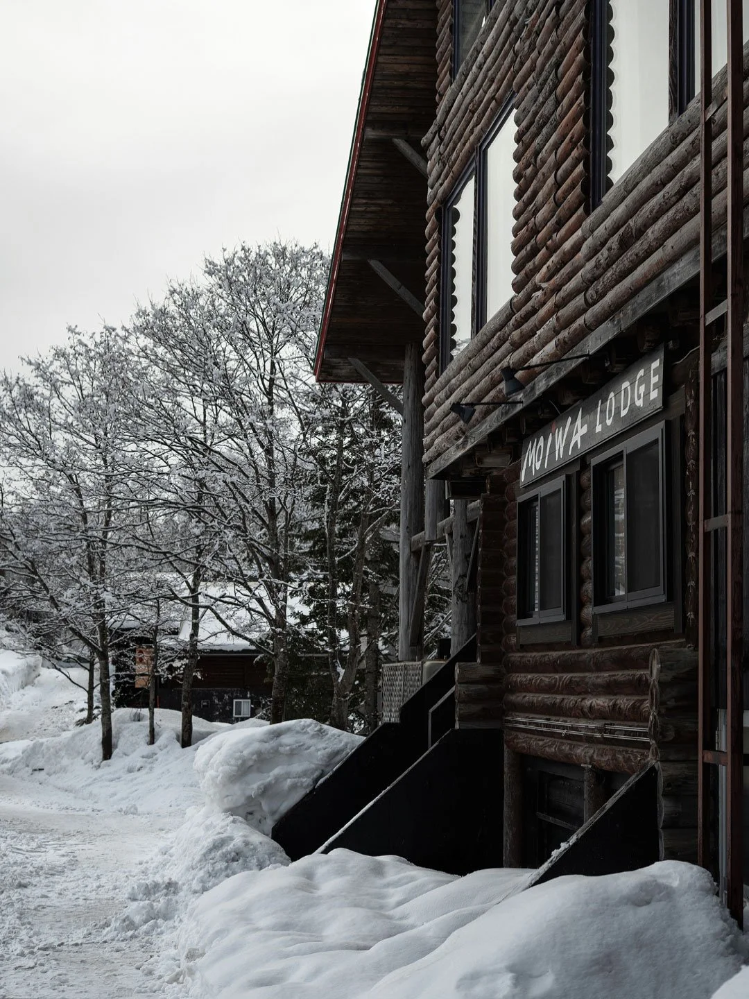Snowy pathway beside traditional wooden lodge in Japan