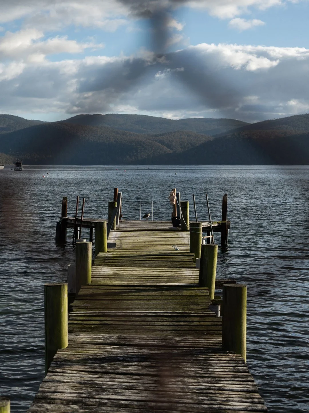 Wooden jetty leading into calm Tasmanian lake