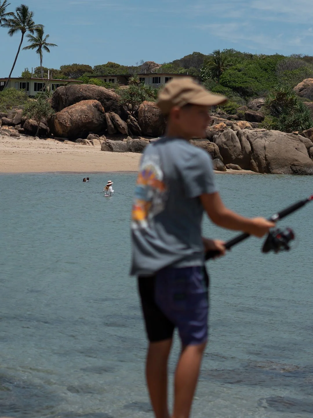 Child walking through shallow tropical waters near rocky beach