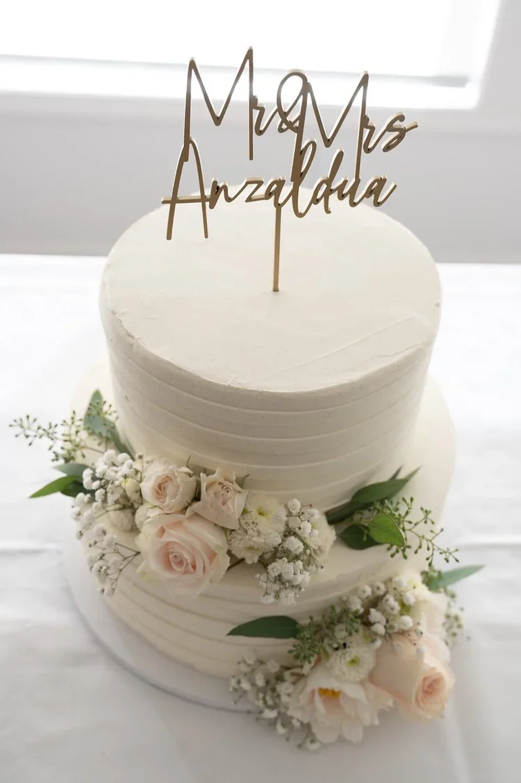 Wedding cake decorated with white flowers and a topper that reads "Mr & Mrs Arzaldia".