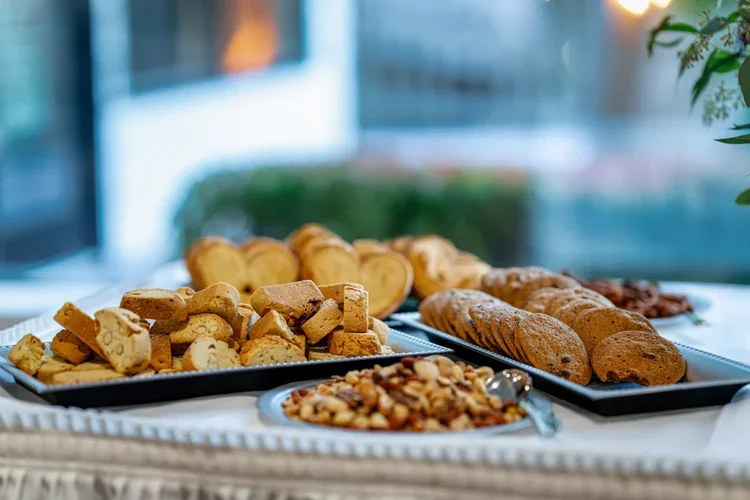 A display of assorted cookies and baked goods on silver trays at a buffet or food station.