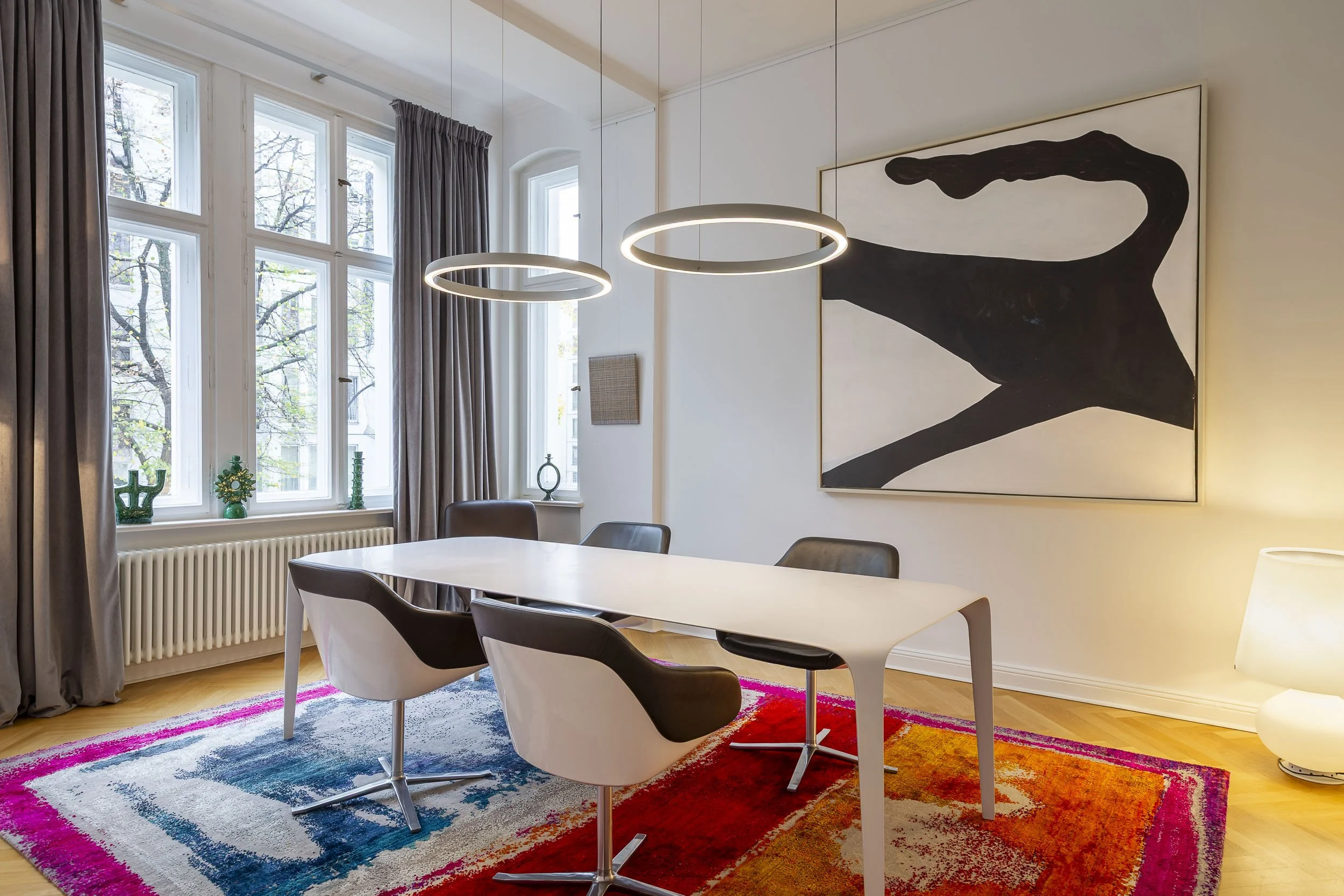 Moderner Essbereich mit Kunst, hohen Fenstern und farbigem Teppich.