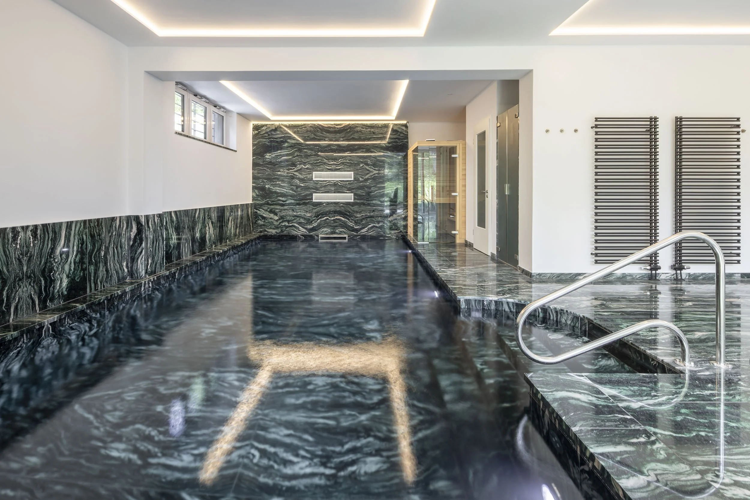 Innenpool mit Naturstein und moderner Wellnessausstattung.