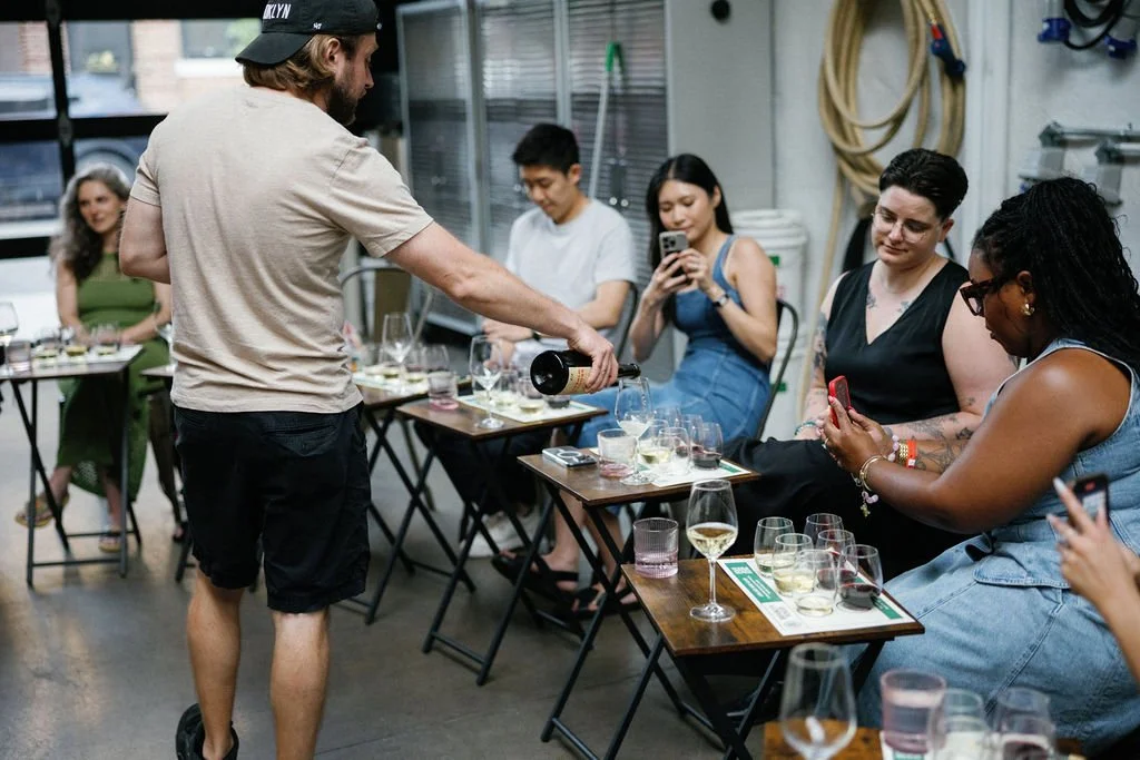A winemaker at Brooklyn Winery pours wines for people attending the winery tour and tasting.
