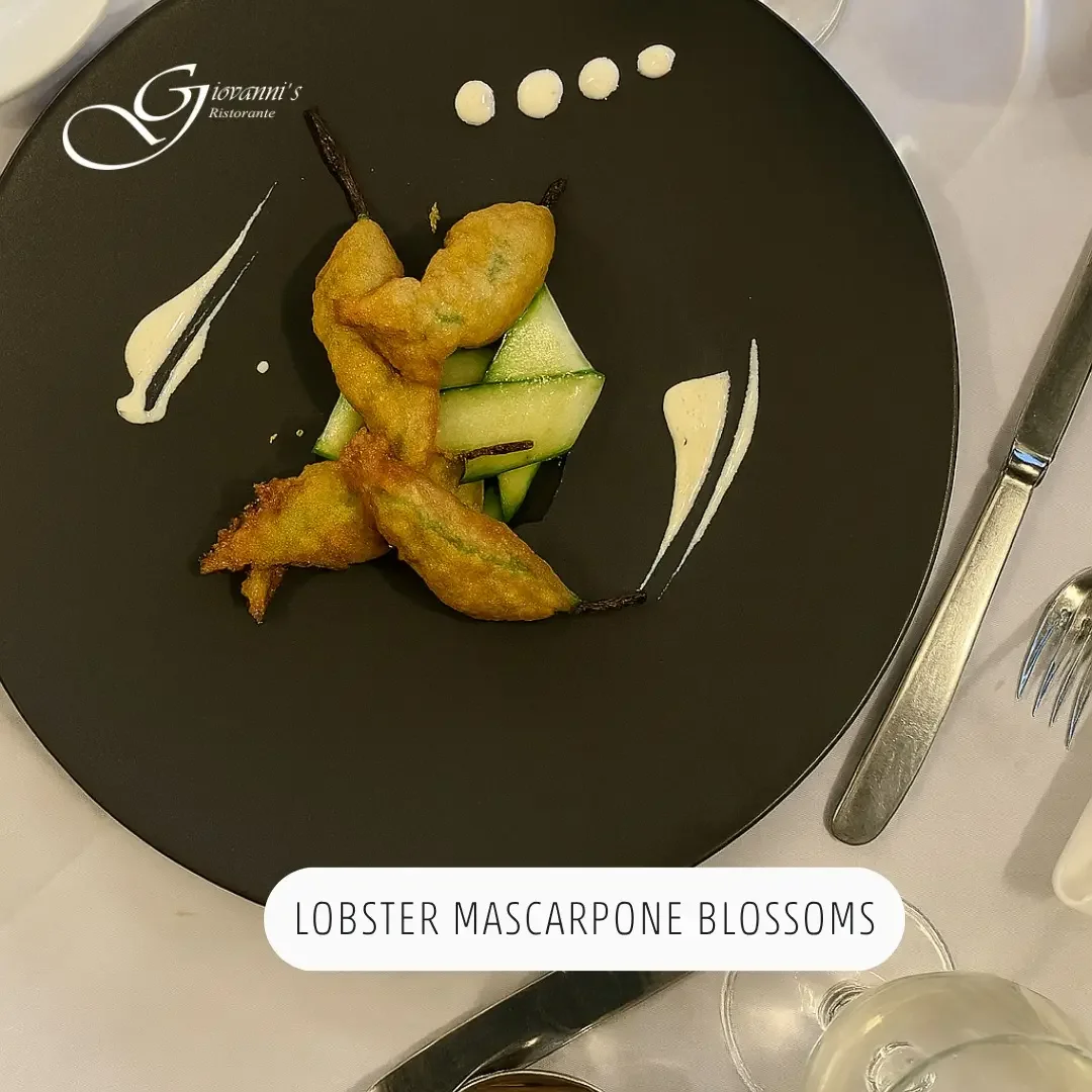 An aerial view of fried zucchini flowers stuffed with lobster mascarpone, presented elegantly on a black plate with cucumber slices at Giovanni's Ristorante