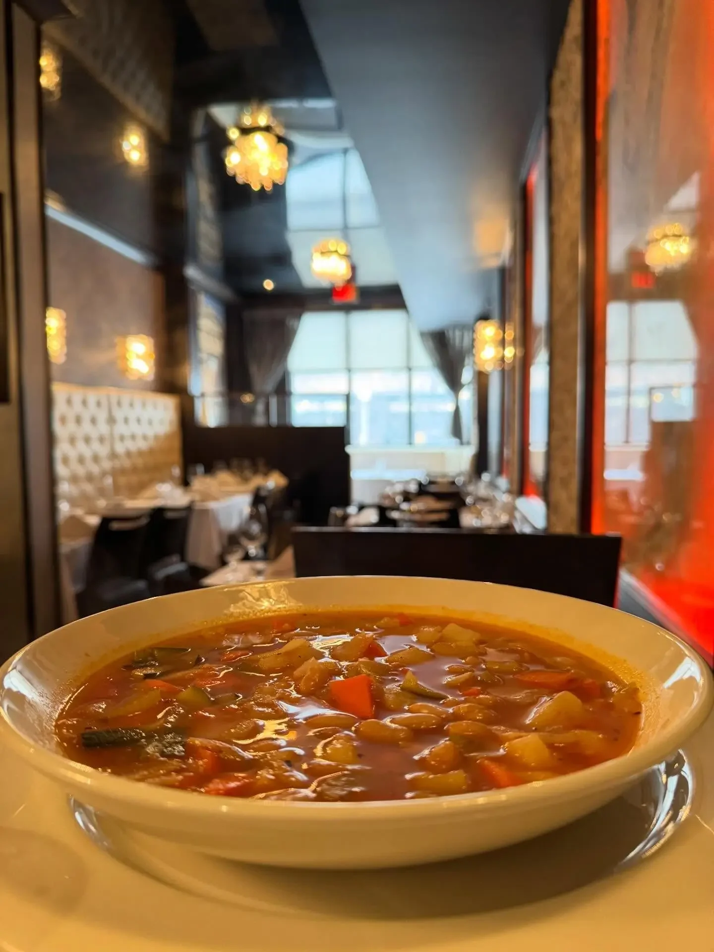 A close-up of a warm bowl of authentic Italian vegetable soup served in the elegant dining room of Giovanni's Restaurant in downtown Ottawa.