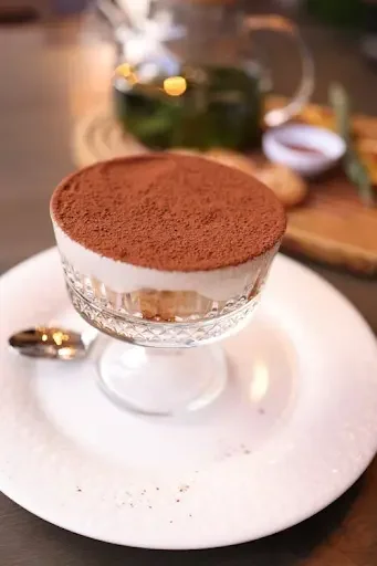 An elegant individual serving of authentic Tiramisu presented in a crystal pedestal glass on a plate, showcasing the best tiramisu in Ottawa available at Giovanni’s Restaurant.