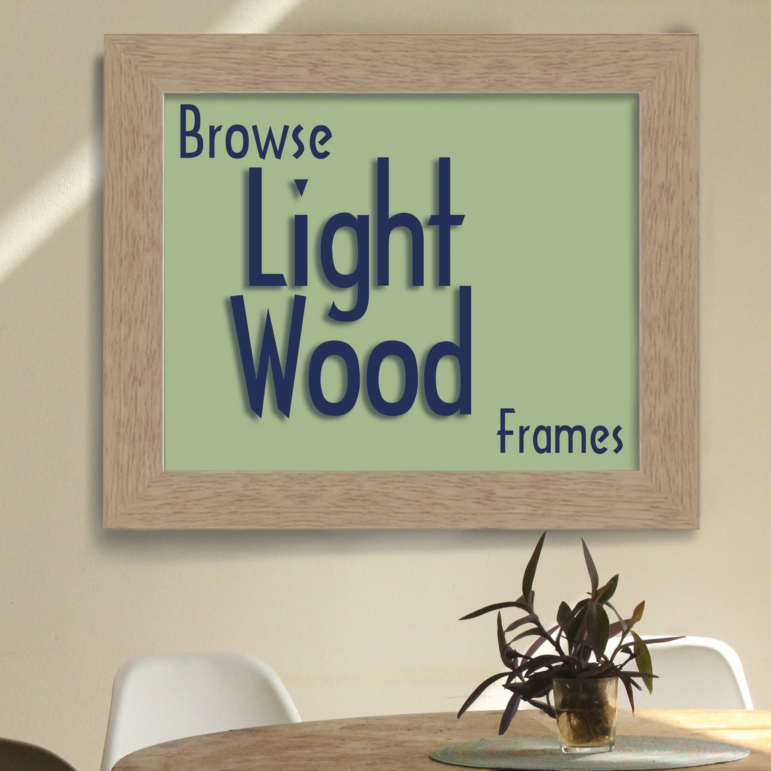 a light maple wood frame hanging on a beige wall above a round kitchen table. Inside the frame is a mint green background and the text "Browse Light Wood Frames"