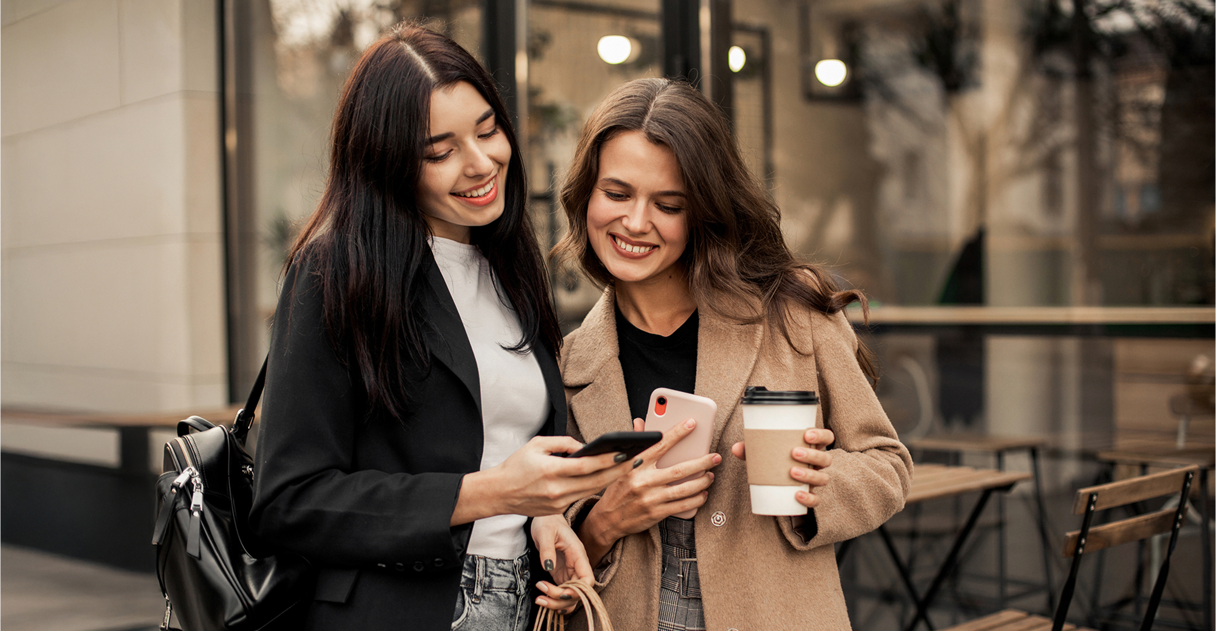 Zwei Frauen reservieren ein Restaurant mit ihrem Smartphone