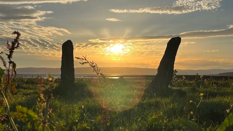 st. ninian's bay at sunset featuring two standing stones in a field.png