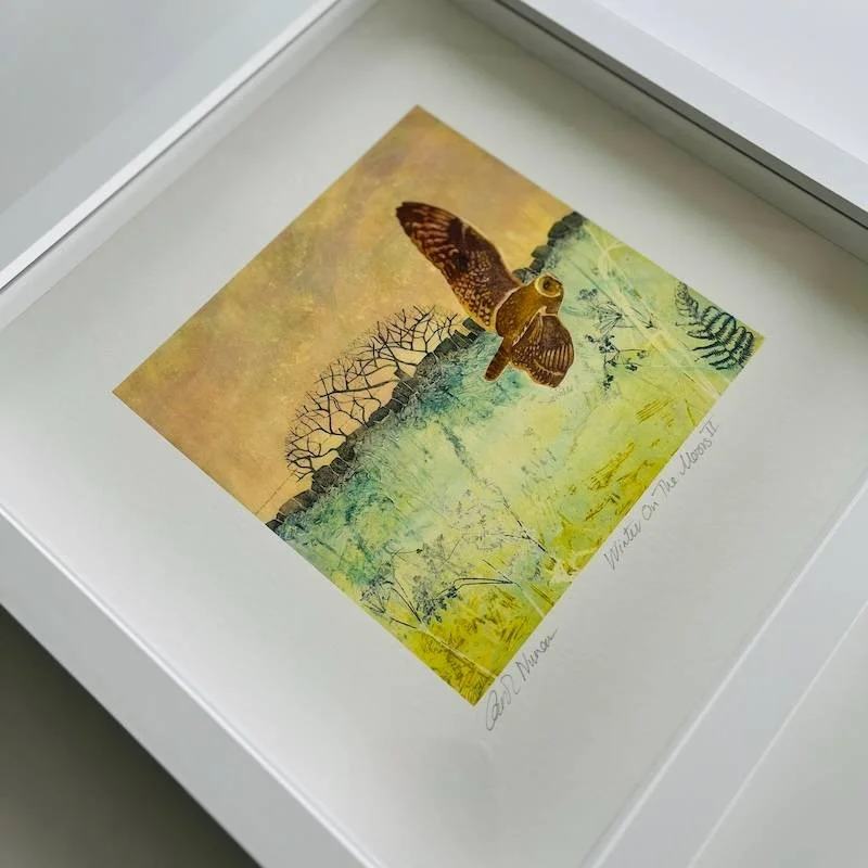 An owl swooping over the moor with a winter tree and stone wall in the background in soft peach, cool grens and greys in a white box frame