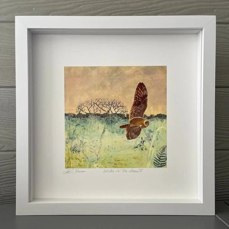 An owl swooping over the moor with a winter tree and stone wall in the background in soft peach, cool grens and greys in a white box frame