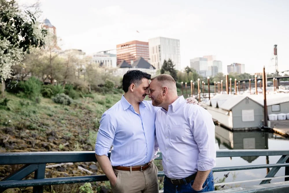 Engaged couple touches foreheads at sunset with the downtown Portland skyline behind them, by their Mt. Hood wedding photographer
