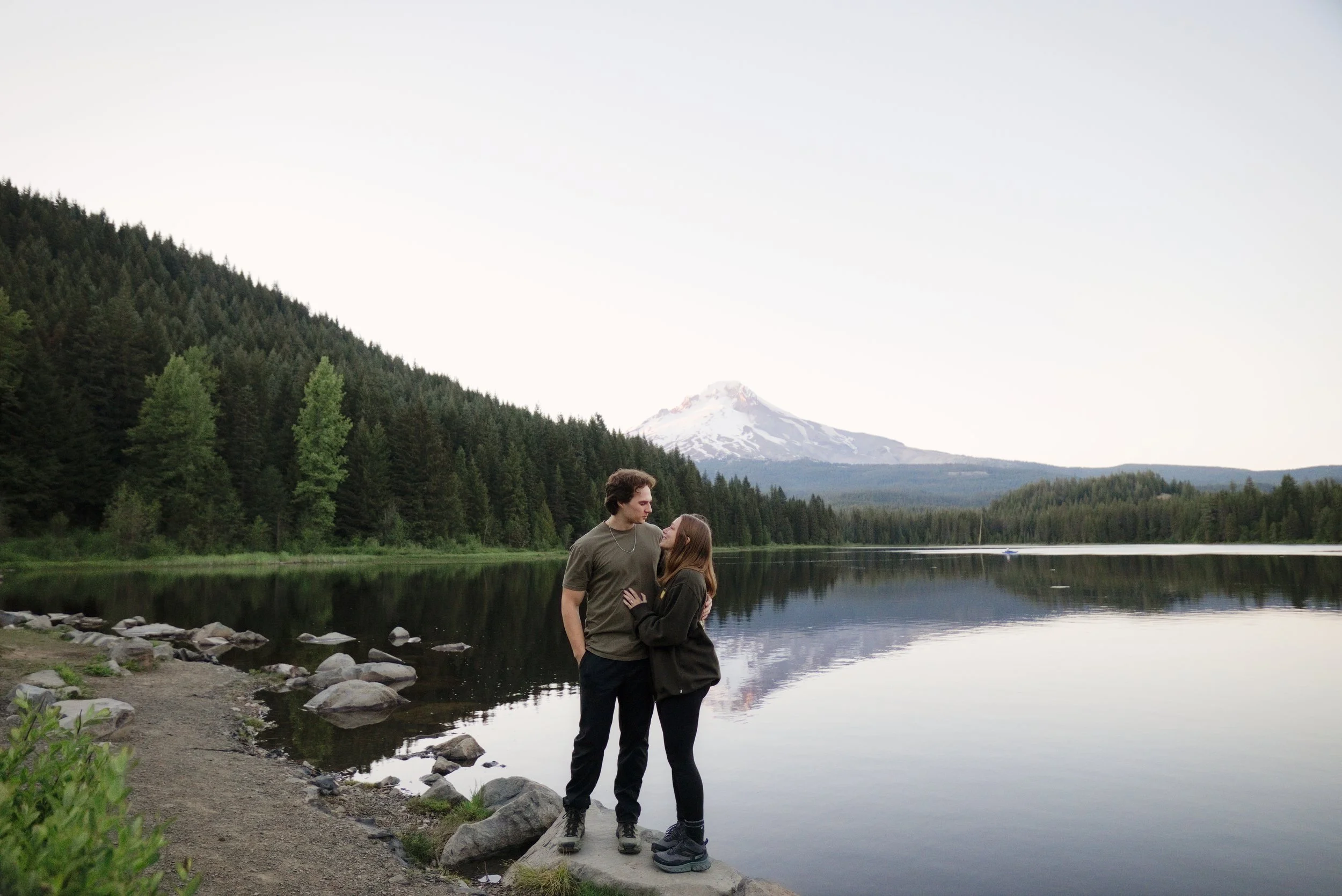 Newly engaged couple standing on the shore of Trillium Lake with Mt. Hood mirrored behind them