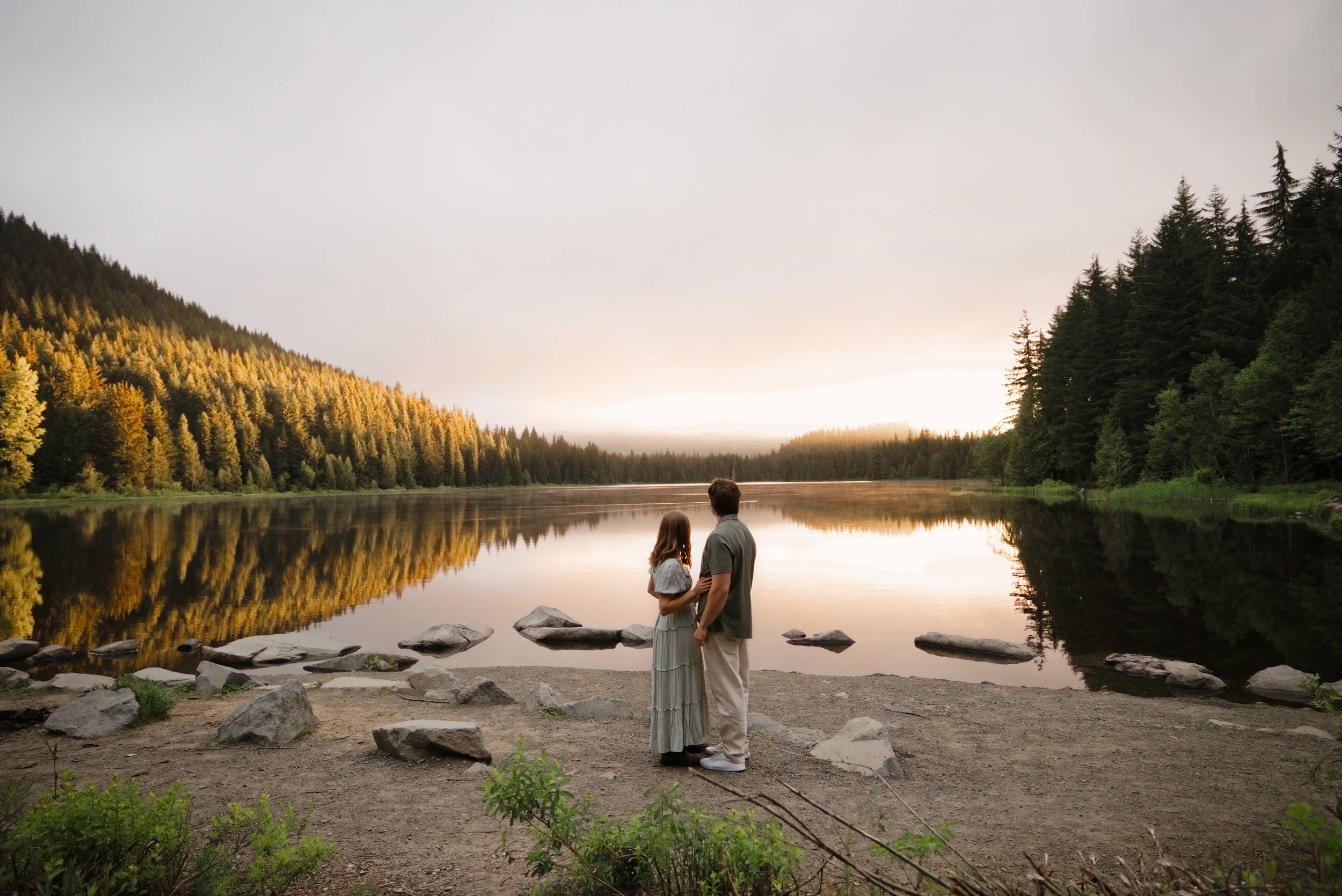 Couple standing together at the edge of Trillium Lake at dusk after their Mt. Hood proposal