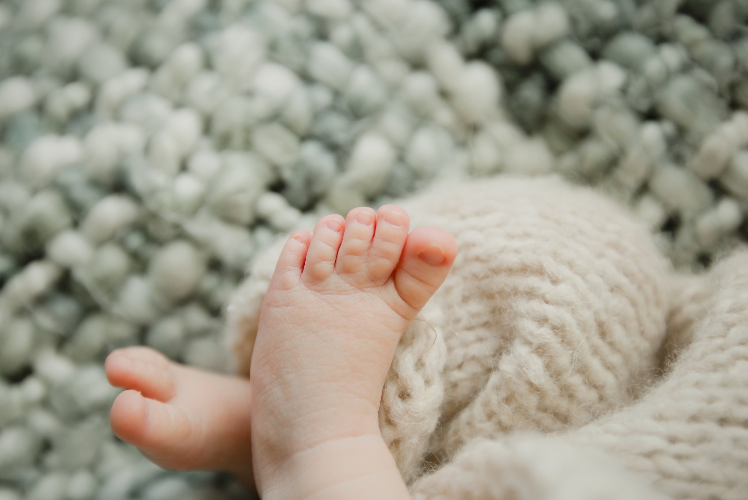 Tiny newborn toes peeking out from a soft knit blanket