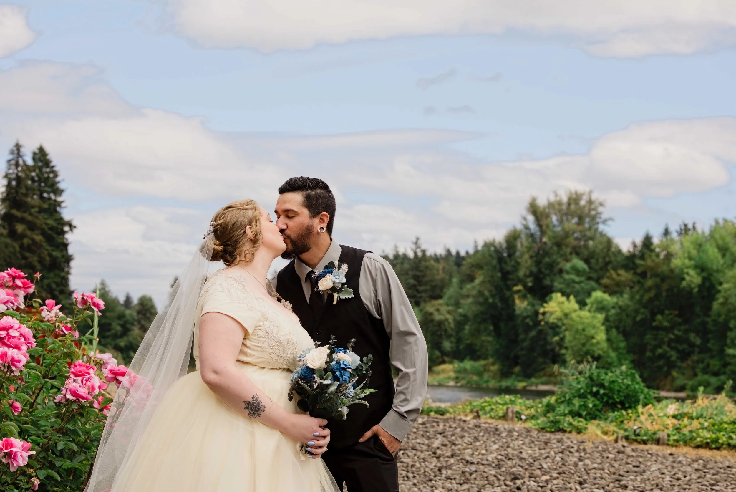 The couple kissing beside the rose garden with the river behind them