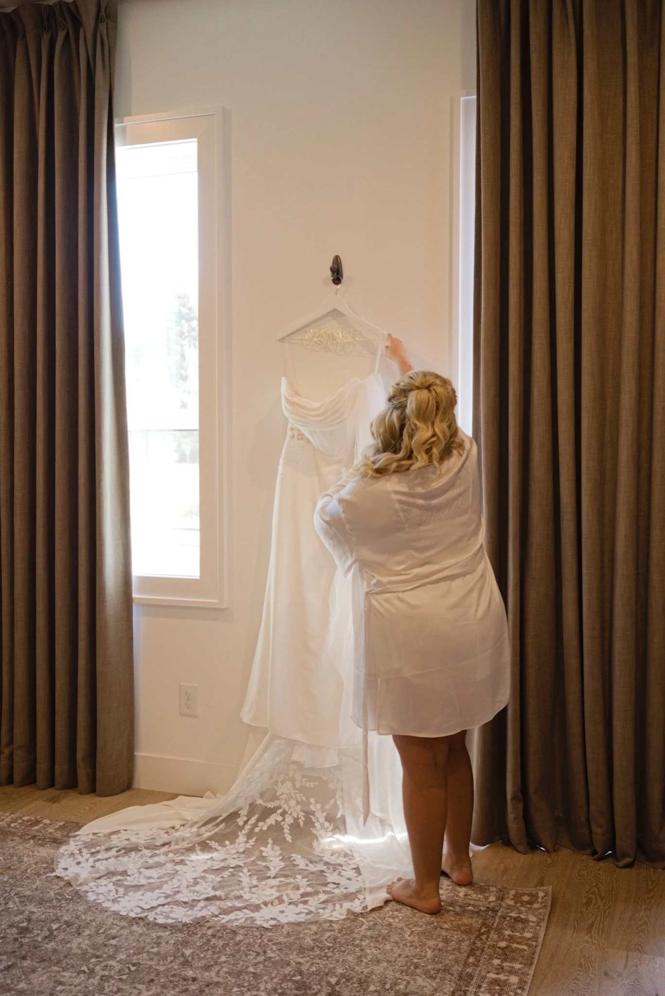 Sarah slipping into her wedding dress by the window