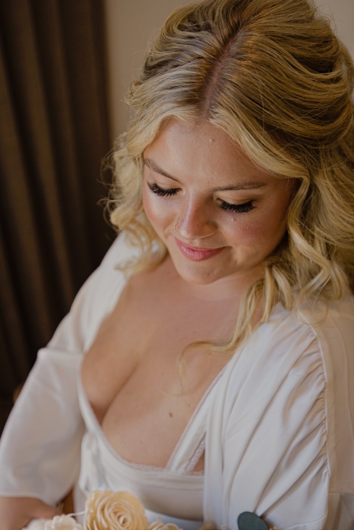 Sarah smiling down at her bouquet while getting ready