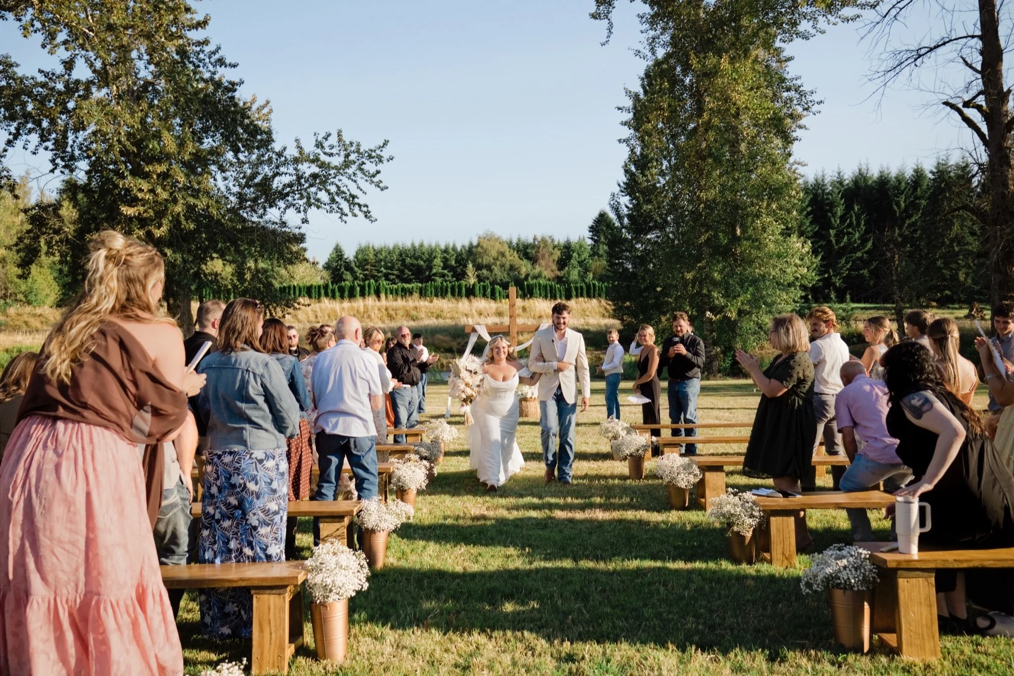 Guests watching the ceremony from wooden benches in the meadow