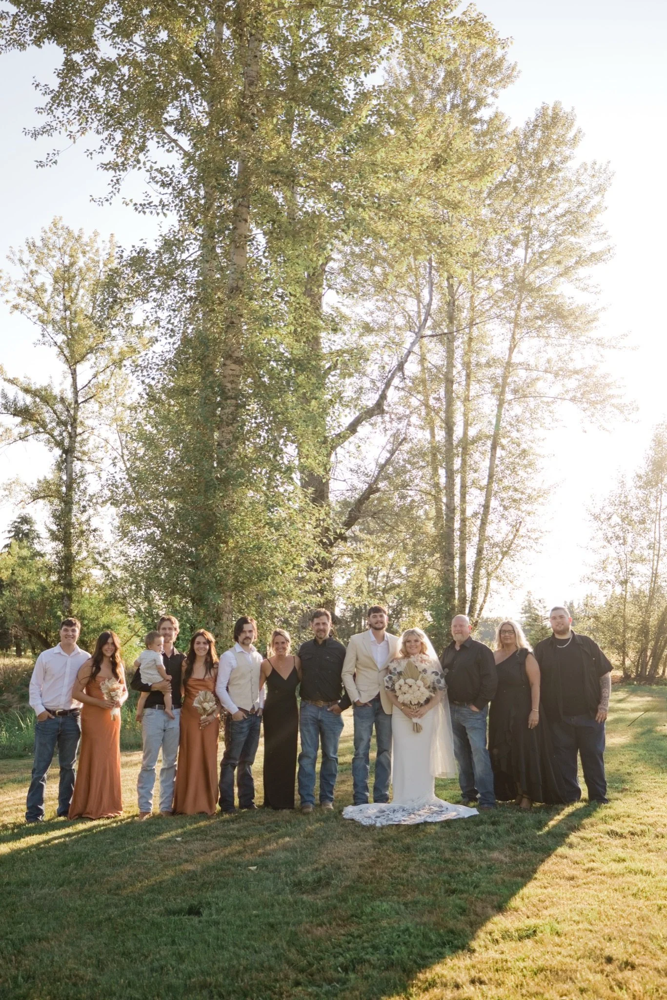 The wedding party in rust, black and cream under the trees
