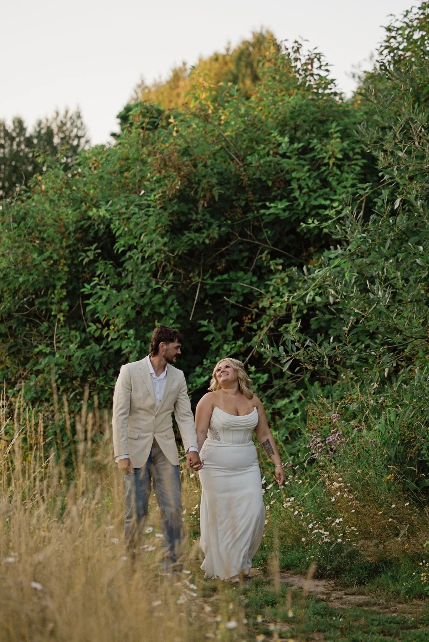 Sarah and Reed in front of the green hedge in the evening