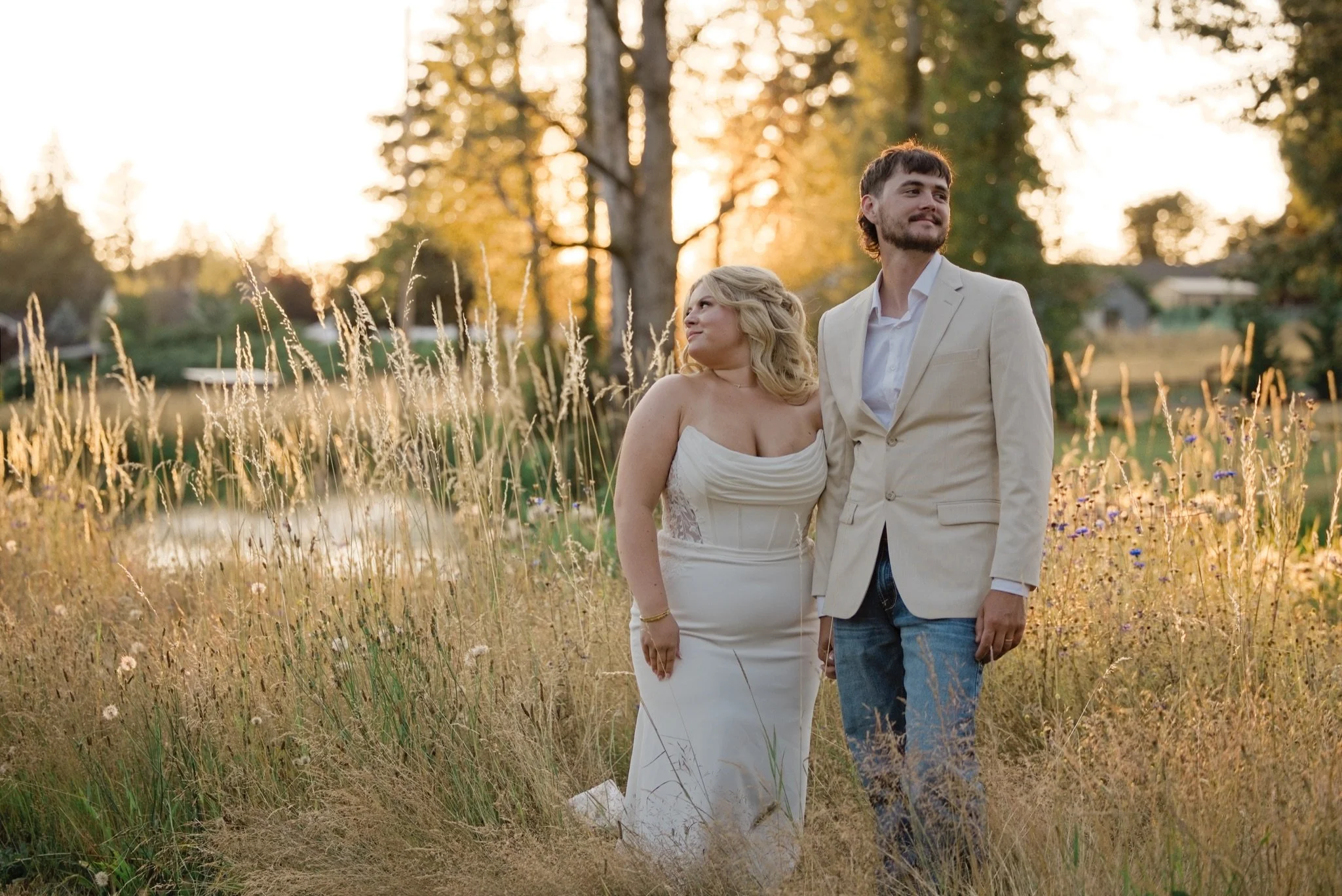 Sarah and Reed walking through the golden grass at sunset