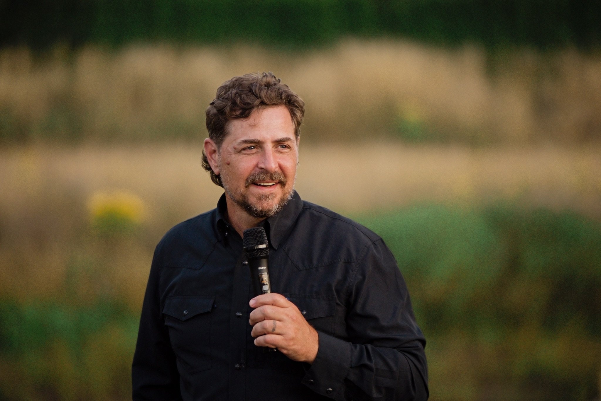 A friend giving a toast with the microphone at dusk