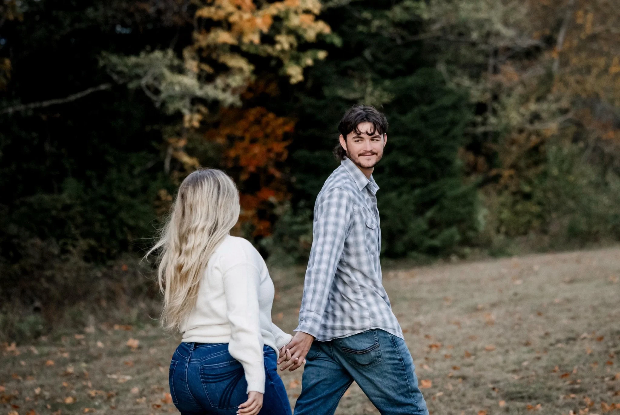 Sarah and Reed walking hand in hand in the fall colors of their engagement session