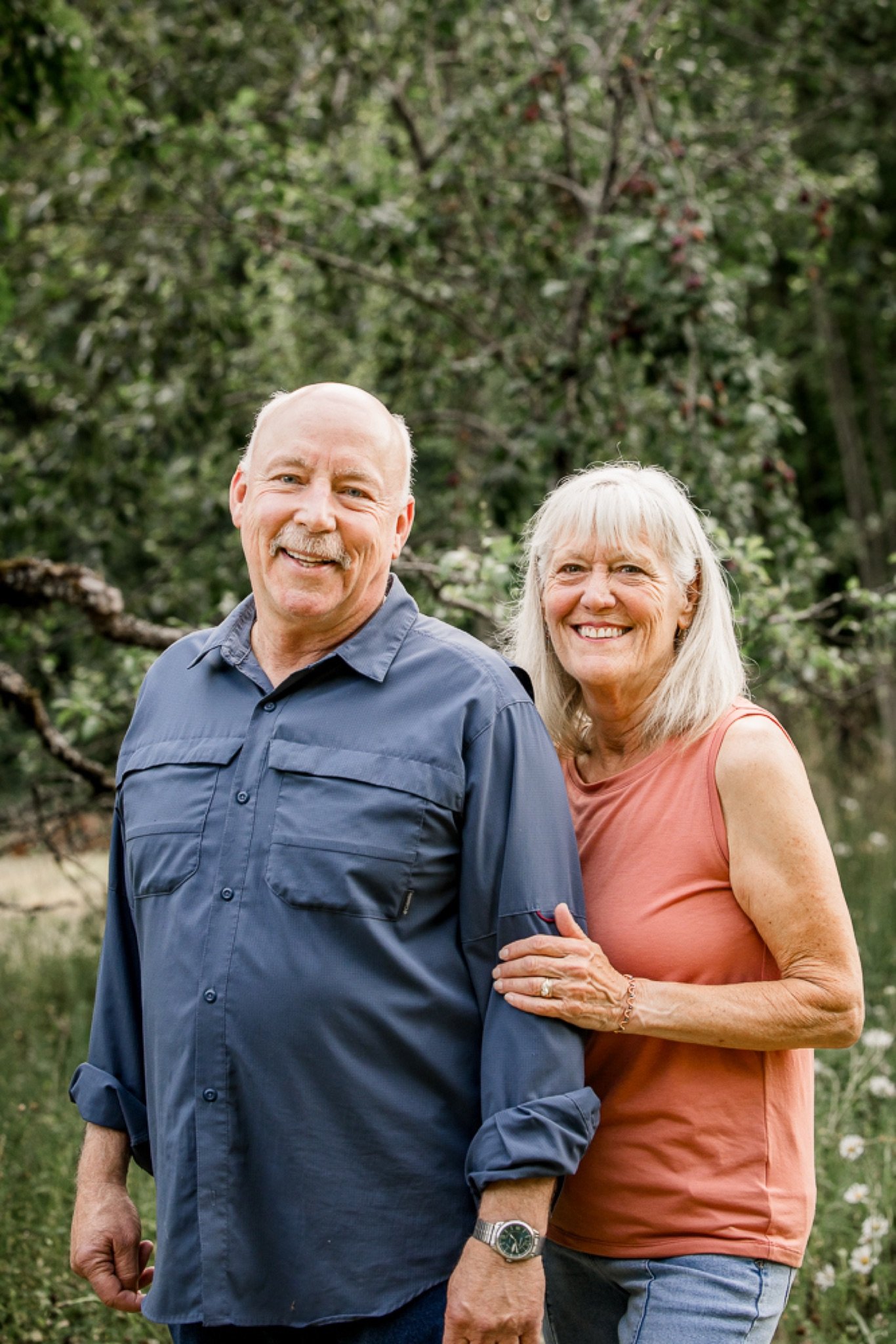 Grandparents standing together under the trees at golden hour in Sandy Oregon