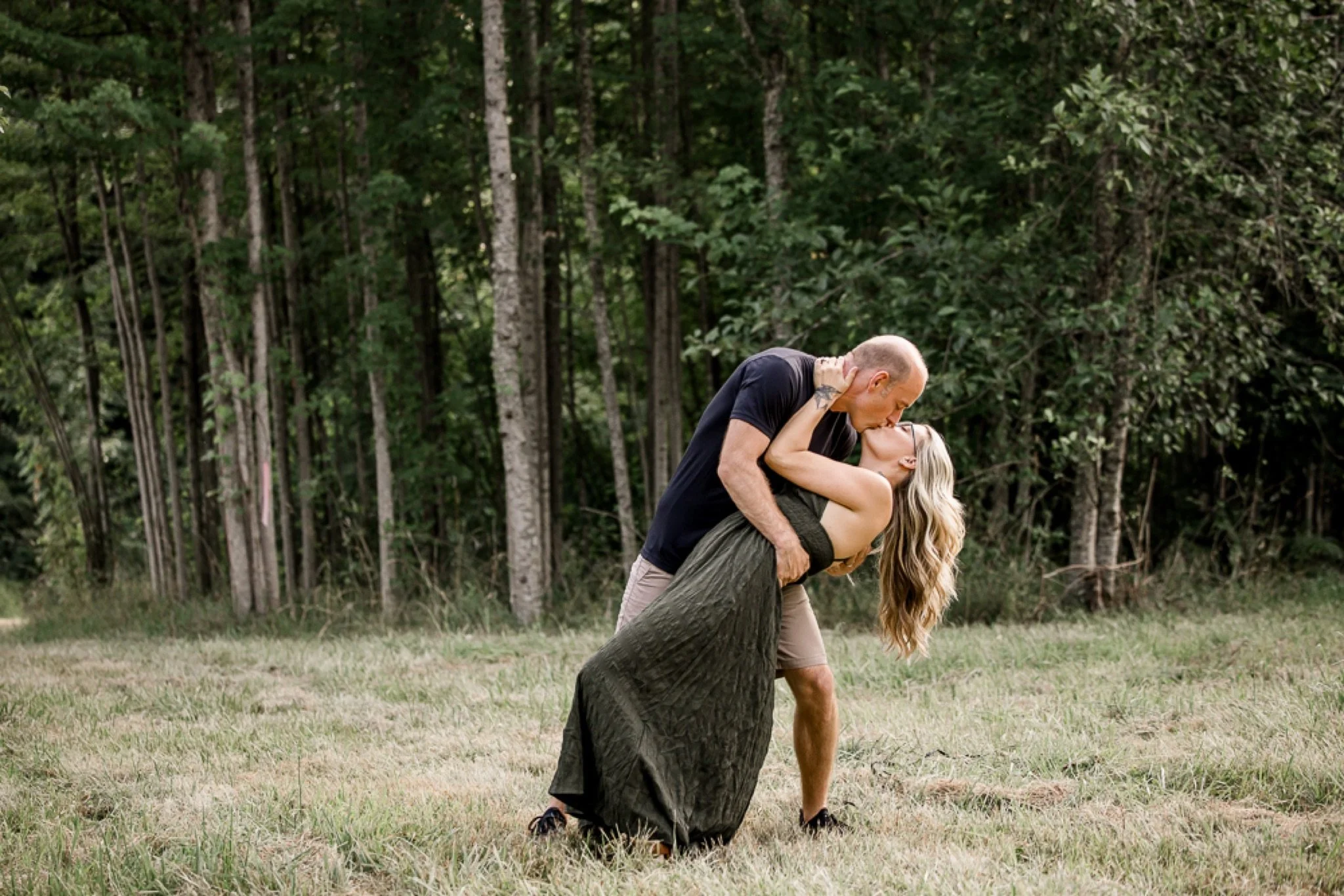 A couple dipping for a kiss in the field at golden hour