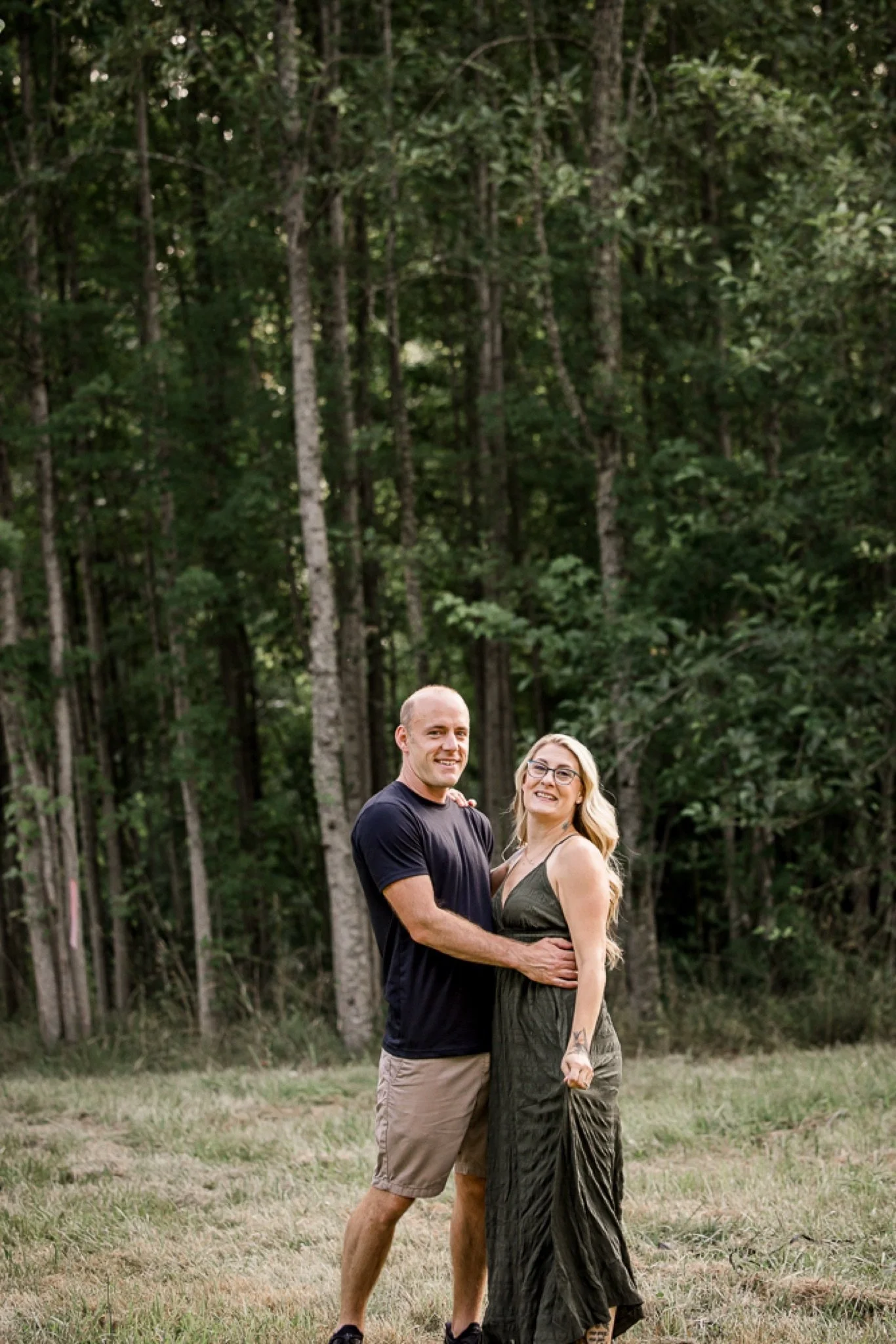 A couple holding each other in front of the trees in the evening light
