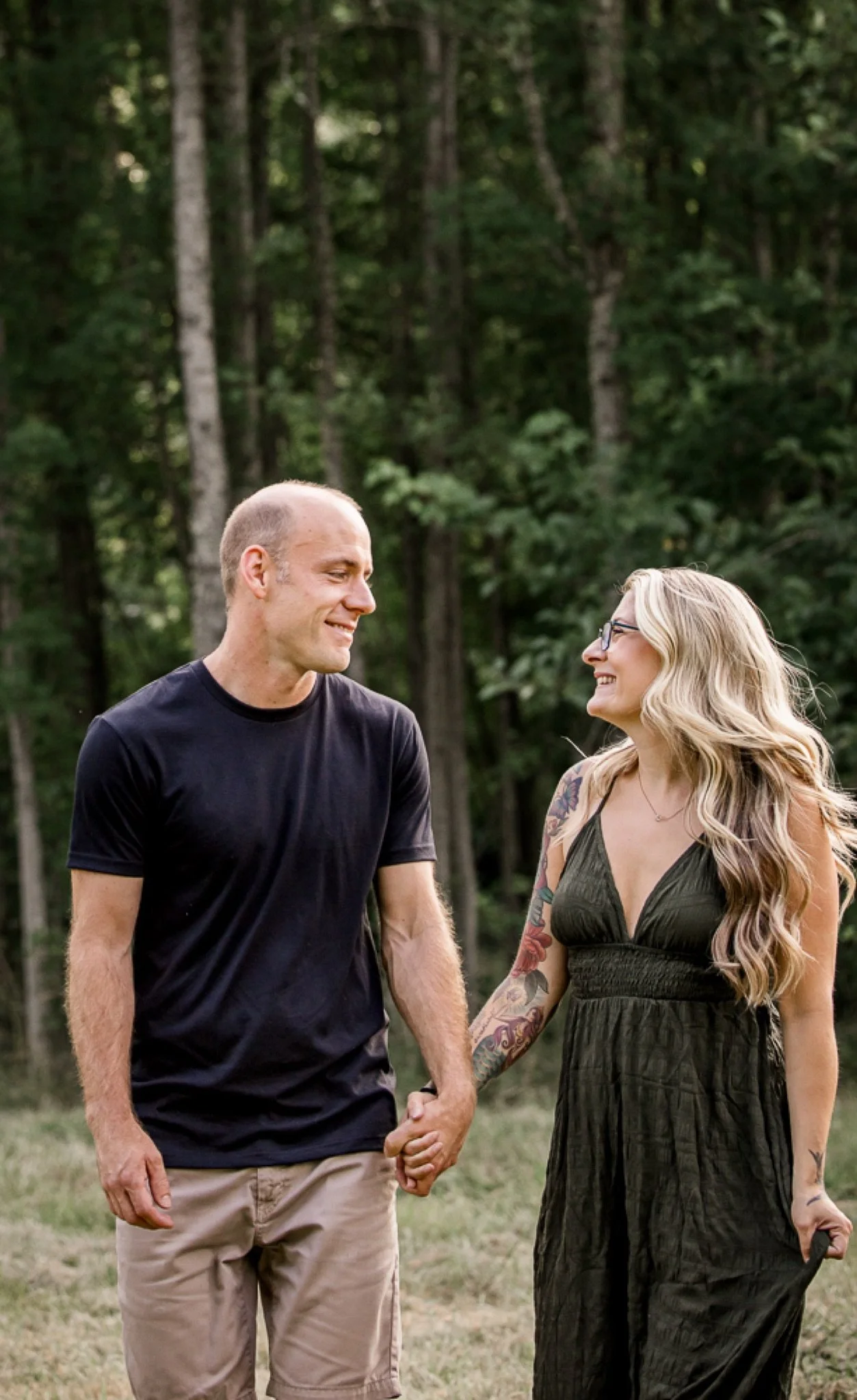 A couple holding hands and smiling at each other in the field