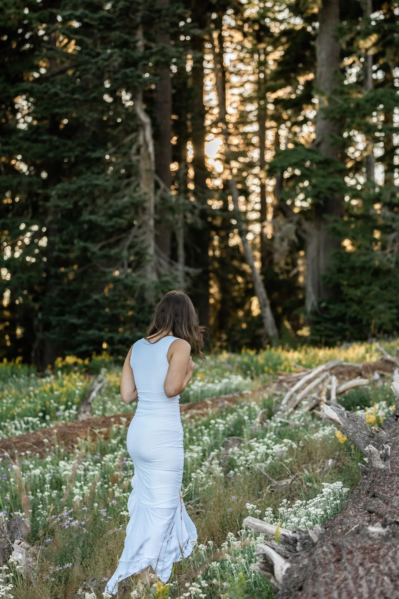 Hailey walking through the alpine wildflowers in her white dress