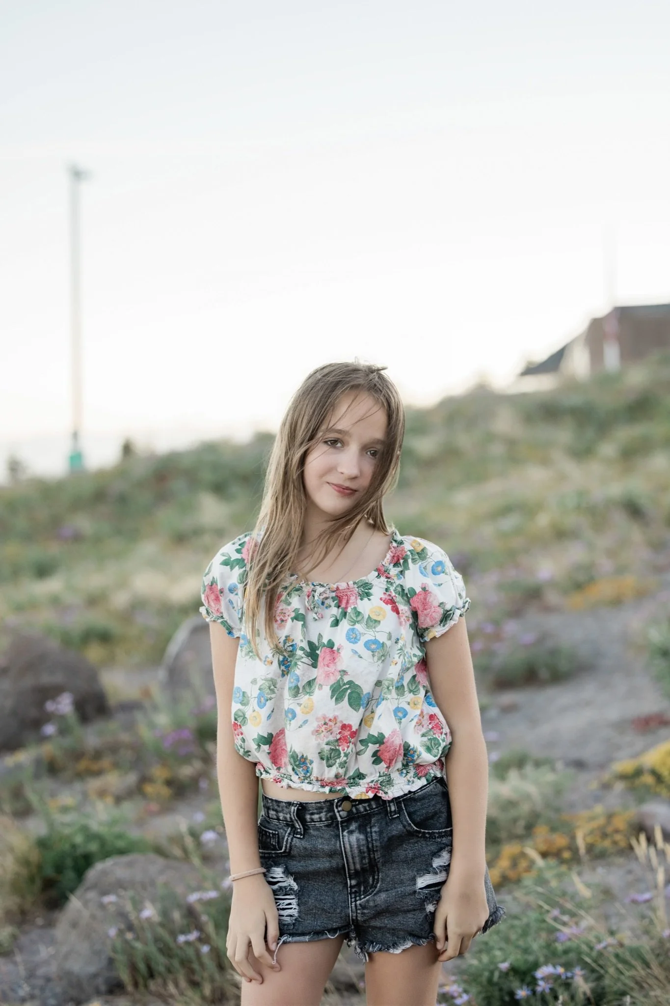 Hailey in a floral top and shorts standing in the meadow