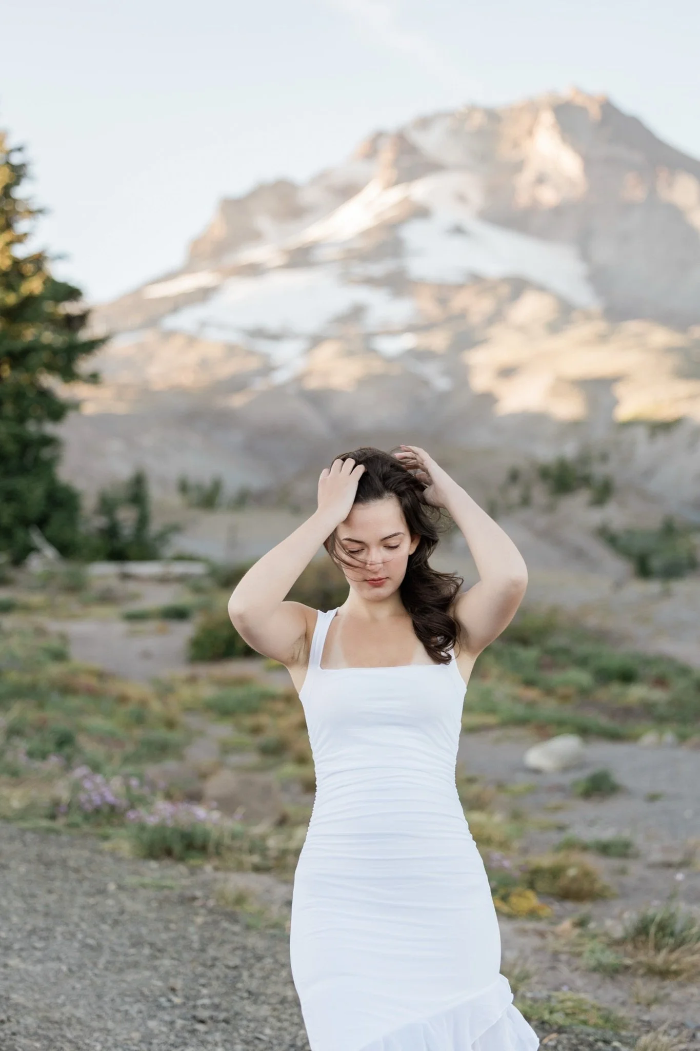 Hailey in a white dress with her hands in her hair below the peak