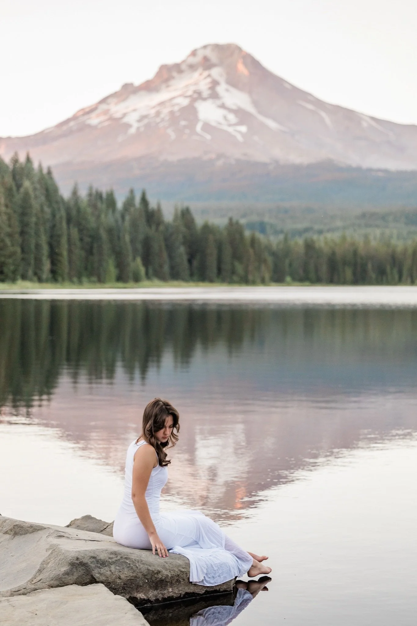 Hailey sitting on a rock at Trillium Lake with Mt Hood reflected