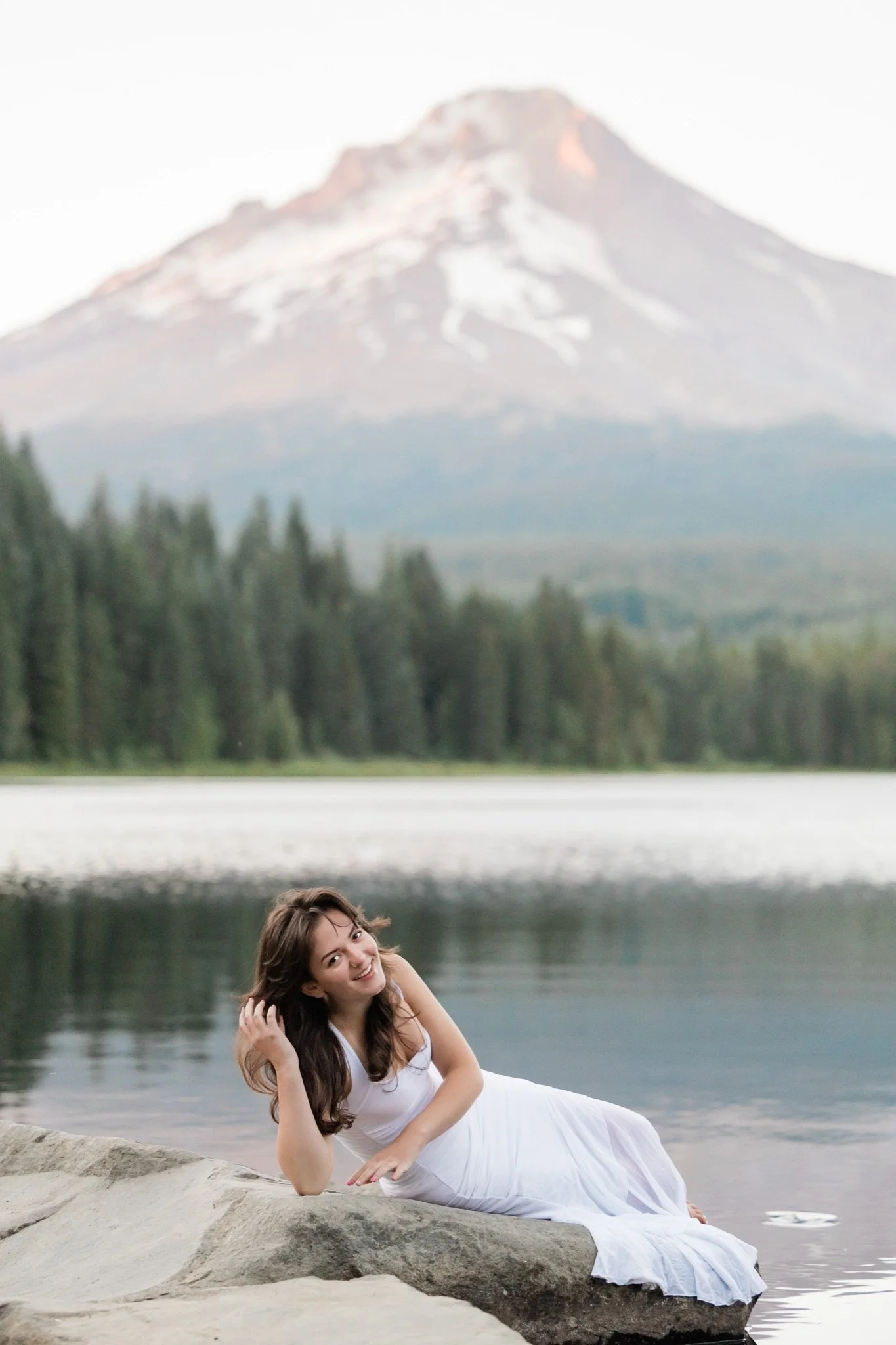 Hailey lounging on the rocks at Trillium Lake with the pink peak behind her