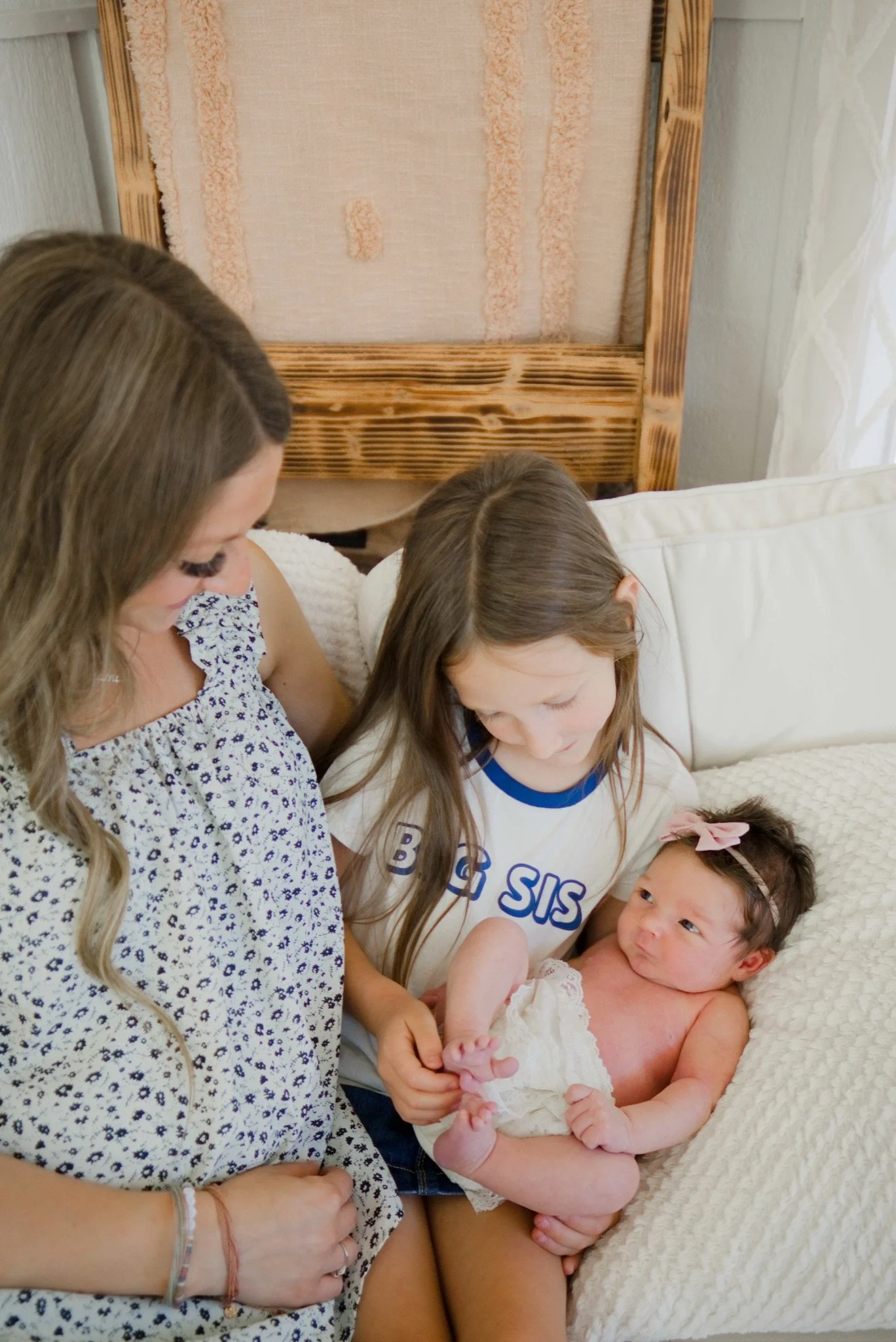 Mom and big sister looking down at newborn Stevie in the studio