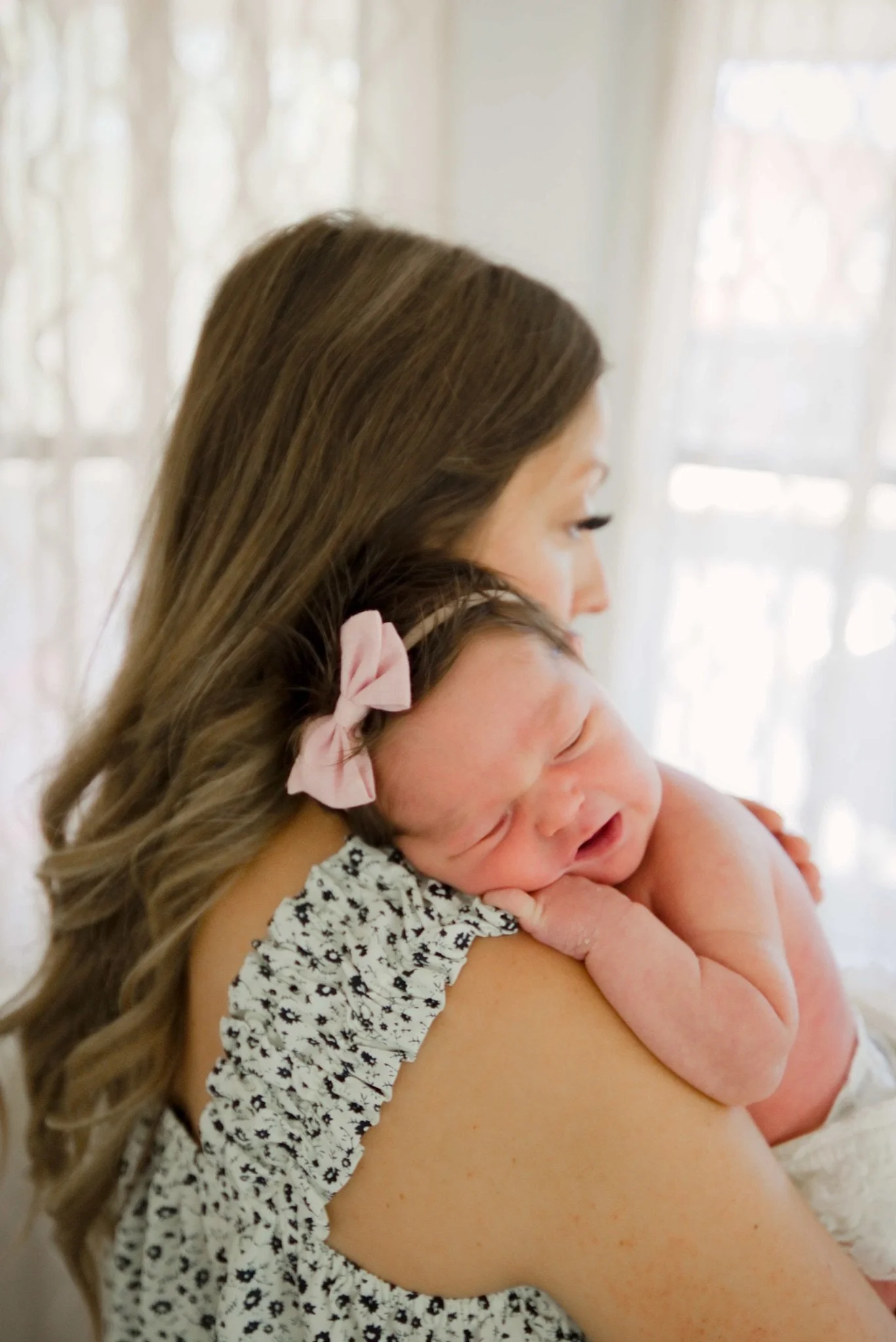 Mom kissing newborn Stevie's head in the window light