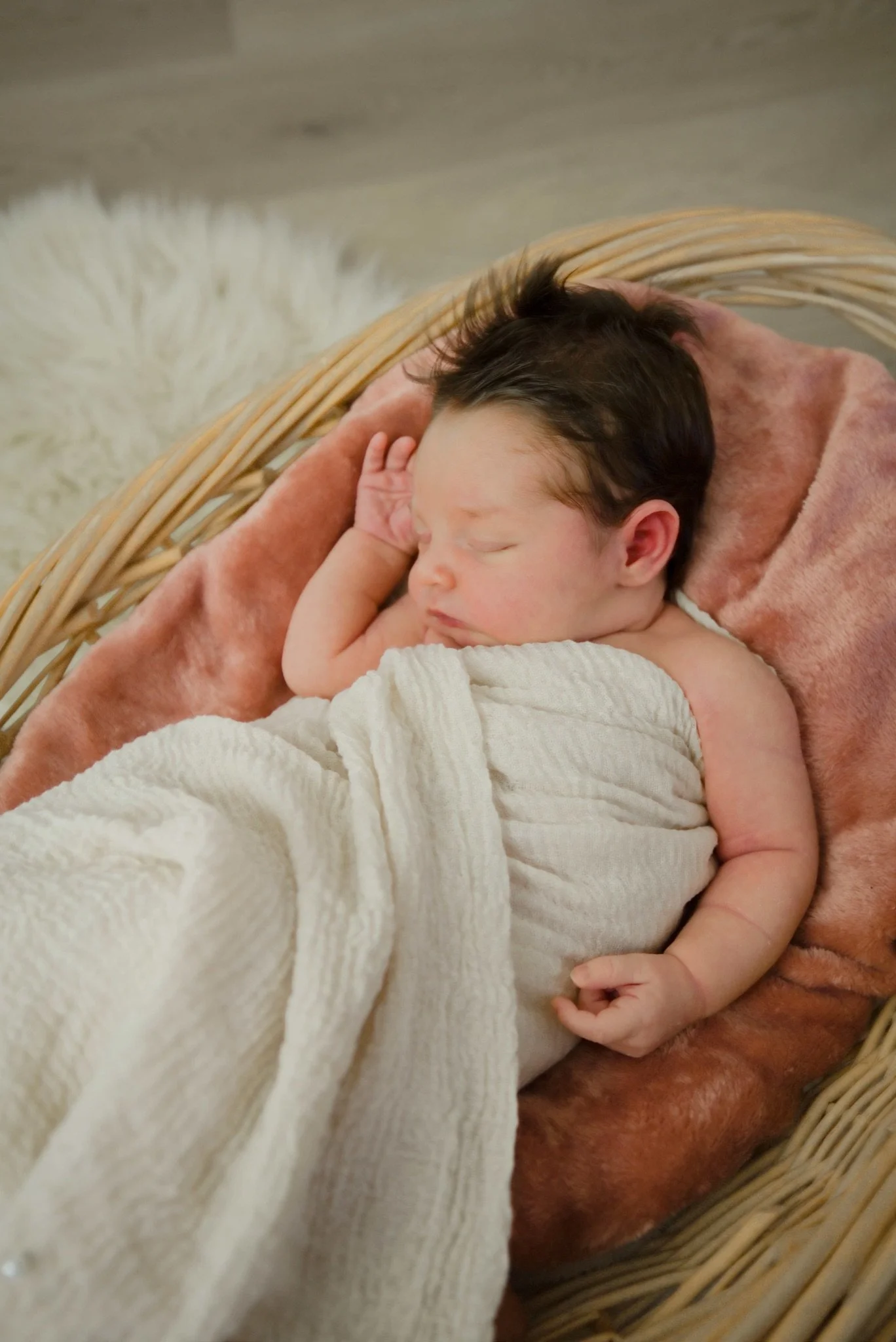 Stevie sleeping in a basket on a cream wrap