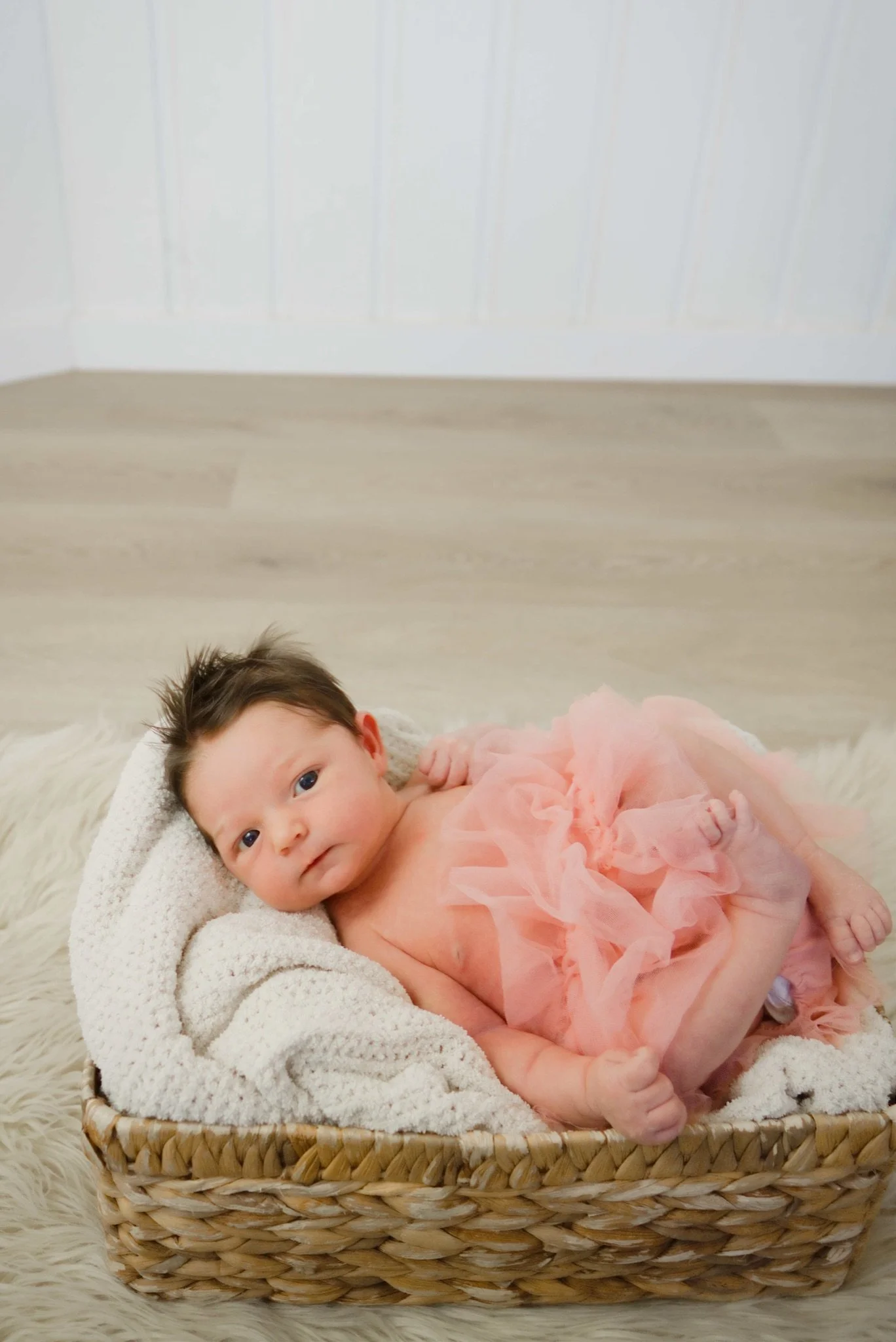 Newborn Stevie asleep in a basket with a pink wrap